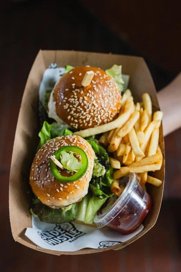 Burger and fries in a cardboard tray with a side of ketchup.