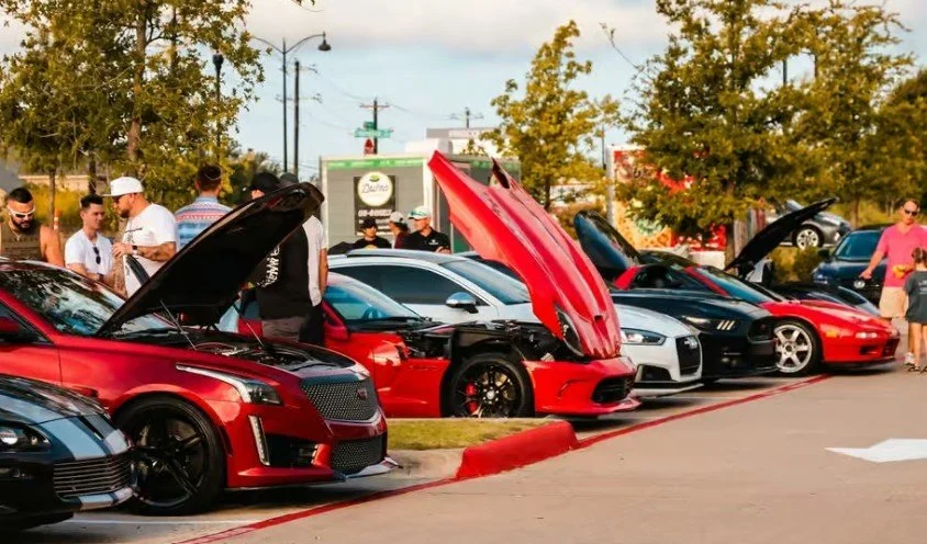 Lineup of sports cars with open hoods at Duino's Cars & Coffee, a monthly car show.