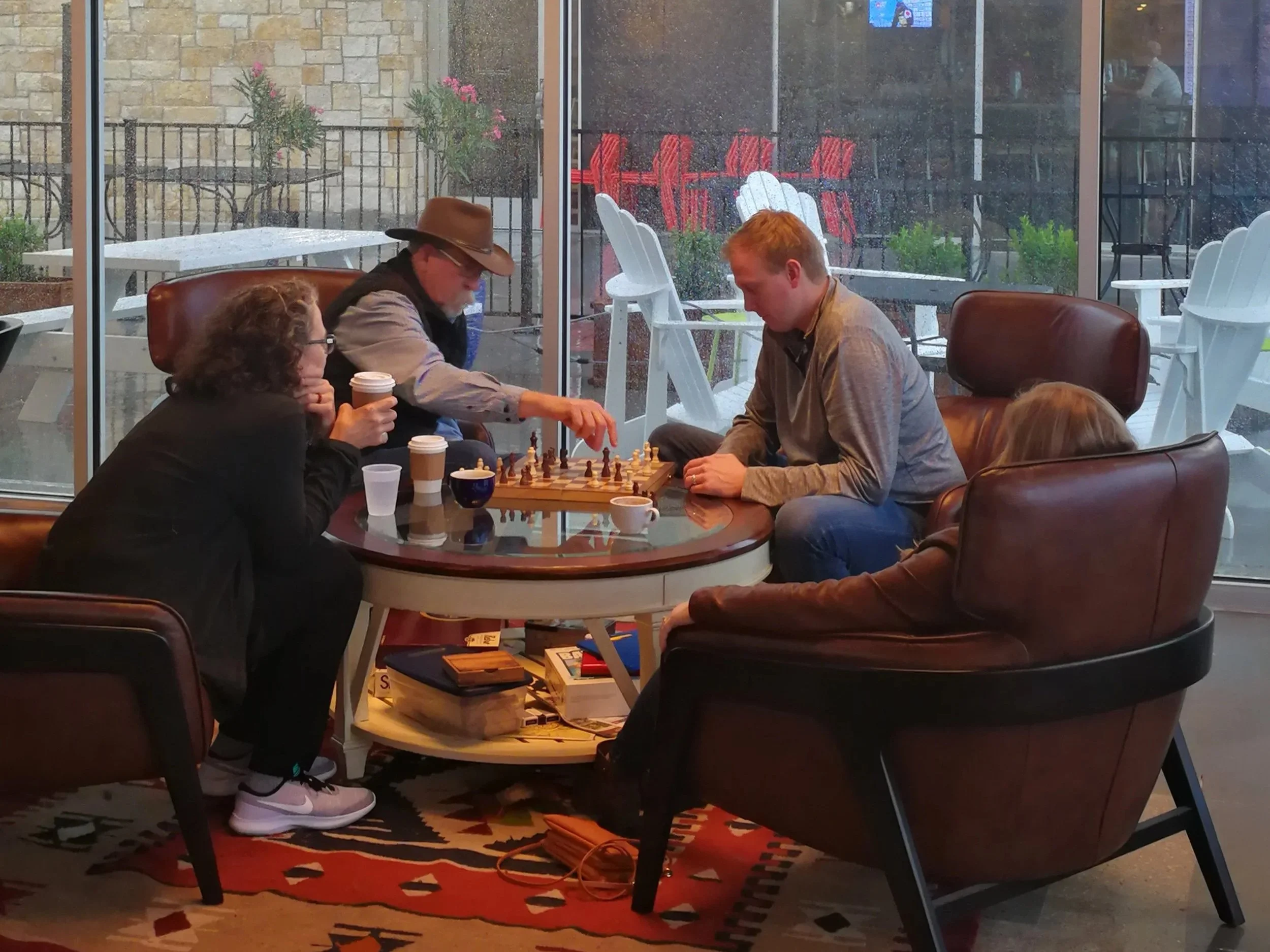 Three people sitting around a table playing chess inside Duino Coffeehouse.