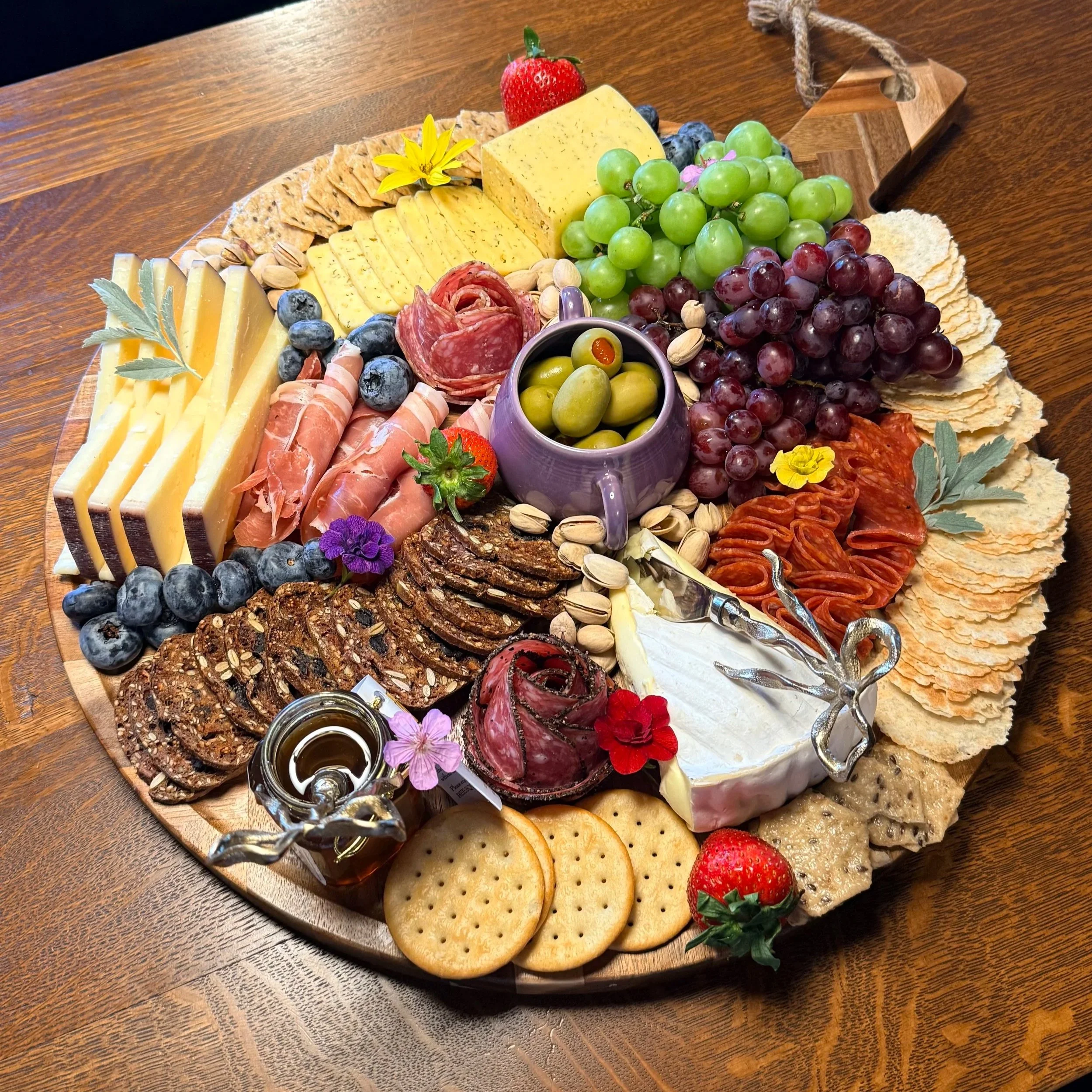 Custom charcuterie board with artisan cheeses, cured meats, crackers, fresh fruit, olives and accompaniments