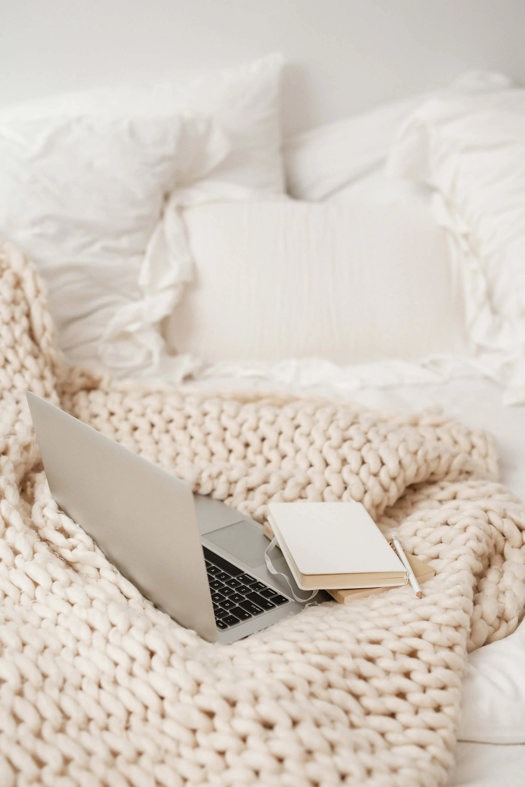 a laptop and notebook on a blanket