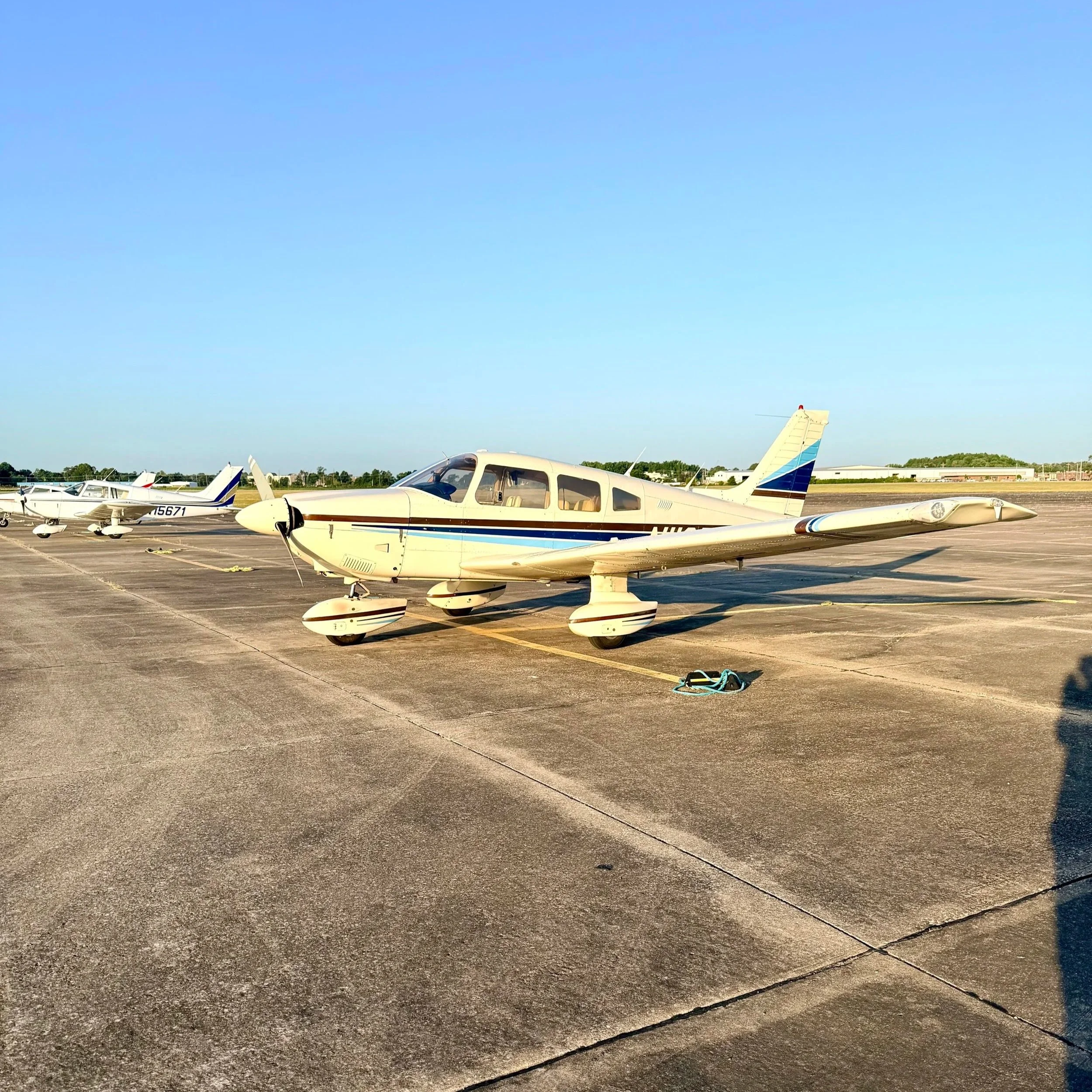 Small private aircraft parked at an airport tarmac on a clear day.