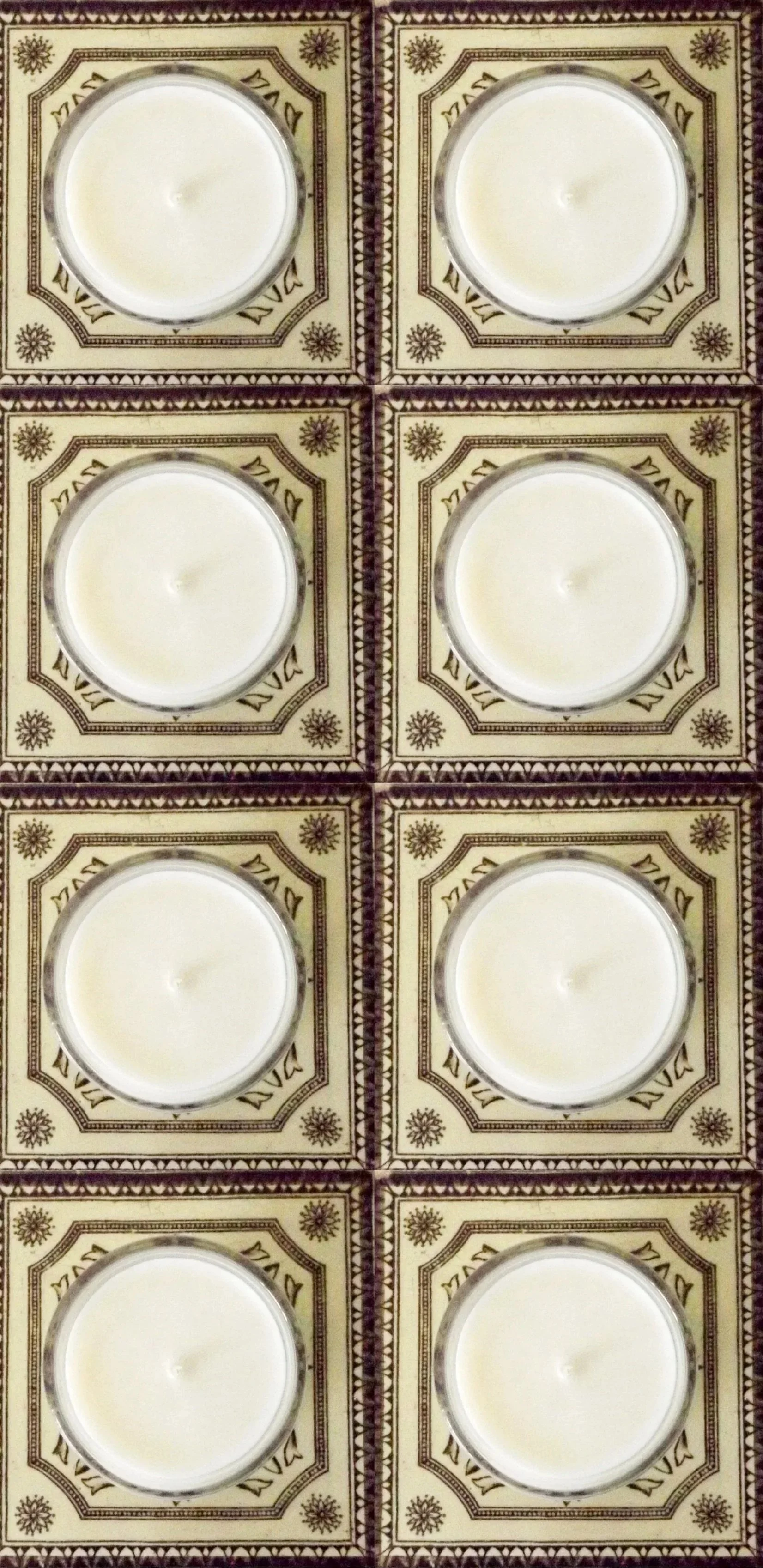Six white candles in glass holders arranged in a 3x2 grid on patterned tiles with intricate designs and text.