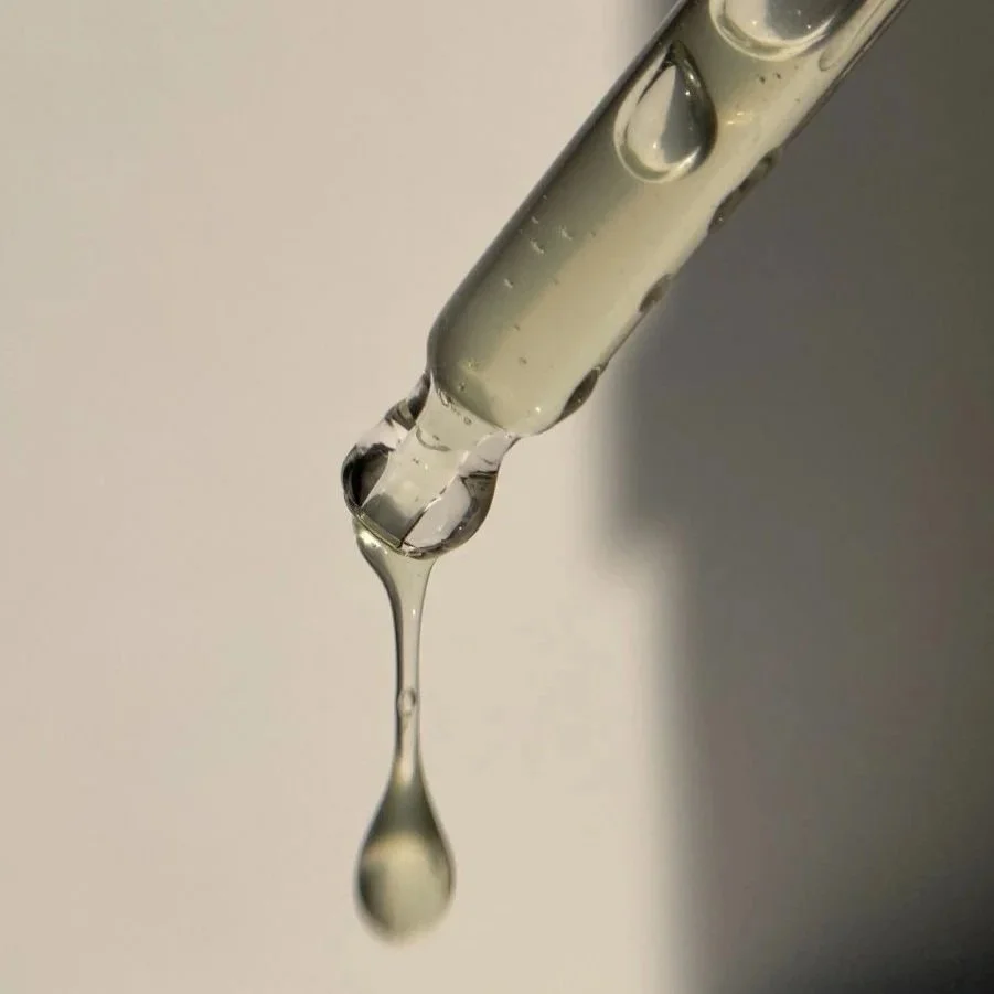 Close-up of a glass dropper releasing a droplet of liquid.