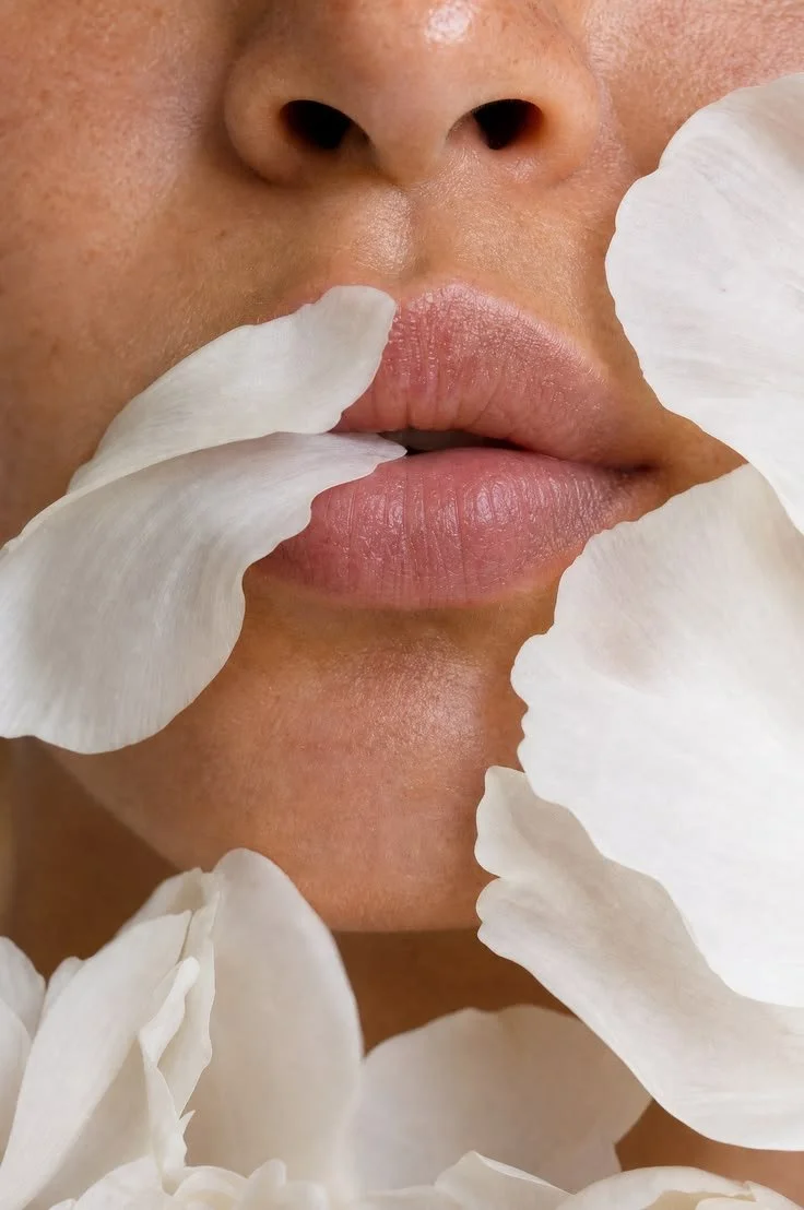 Close-up of a woman's lips surrounded by white flower petals.