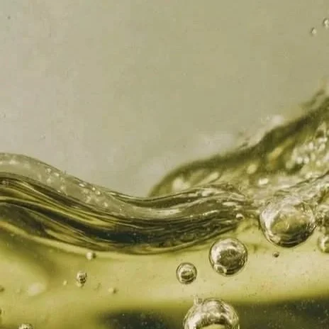 Close-up of a splash of greenish-yellow liquid with bubbles.
