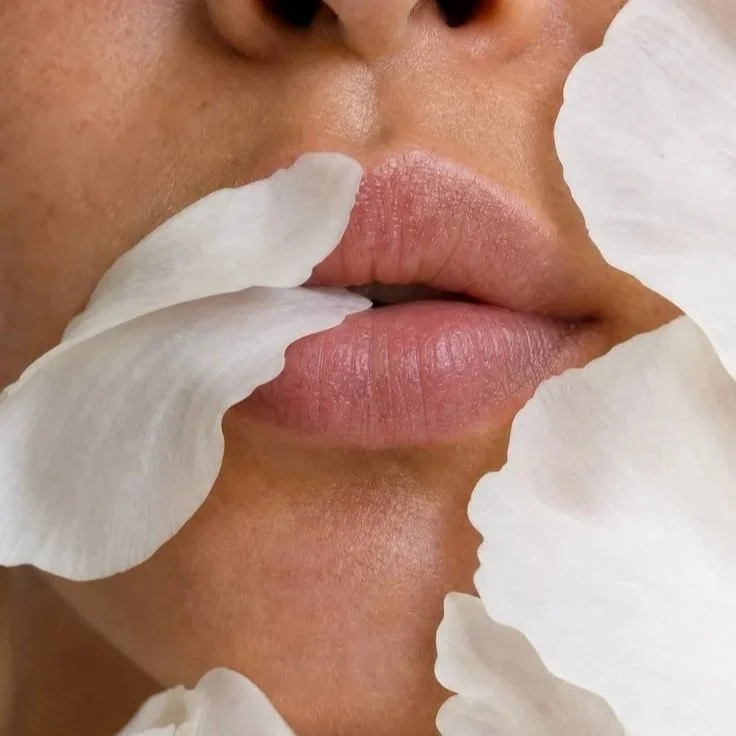 Close-up of a person's lips surrounded by white flower petals.