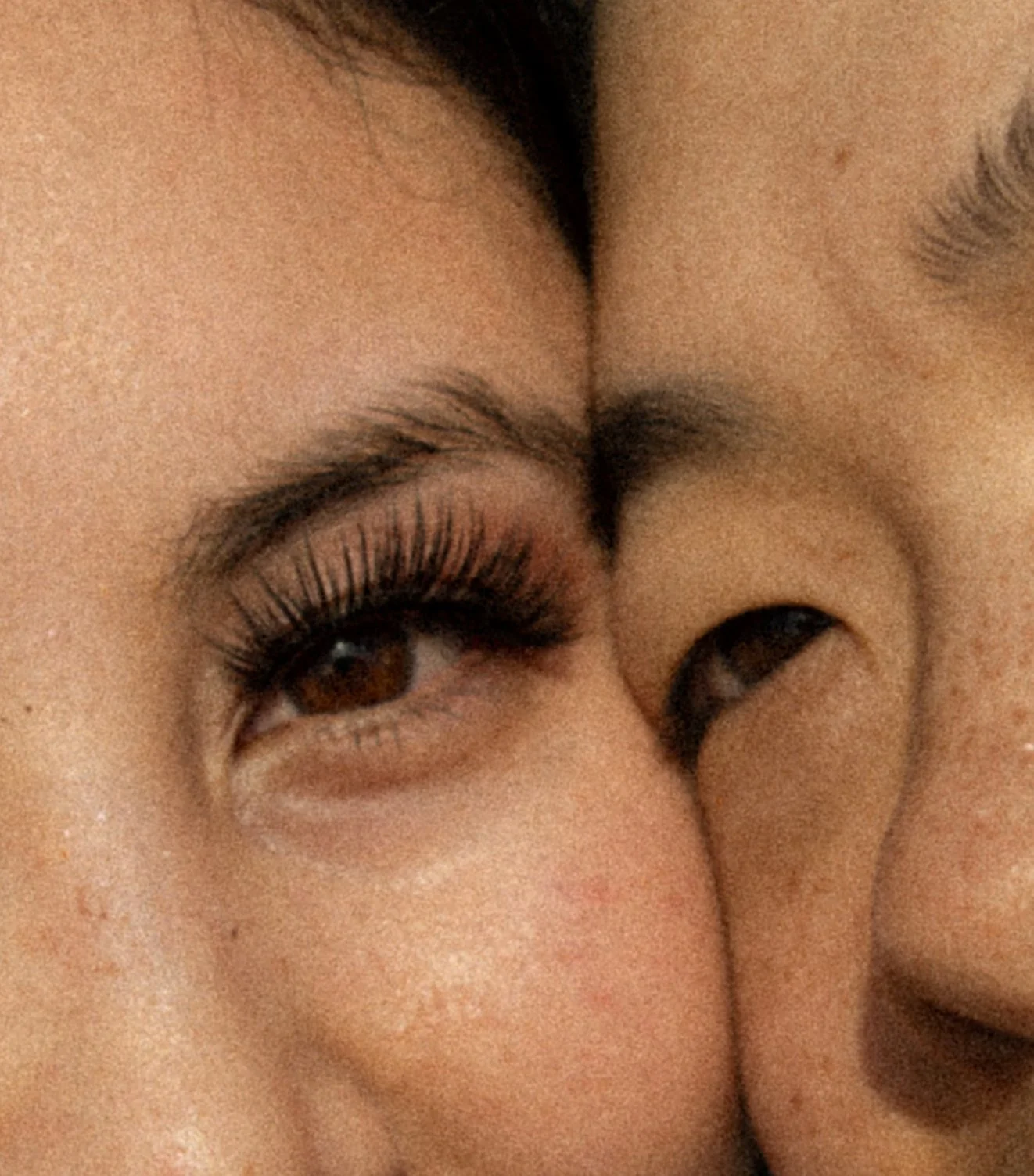 Close-up of a woman winking and smiling, with eye makeup and long eyelashes.