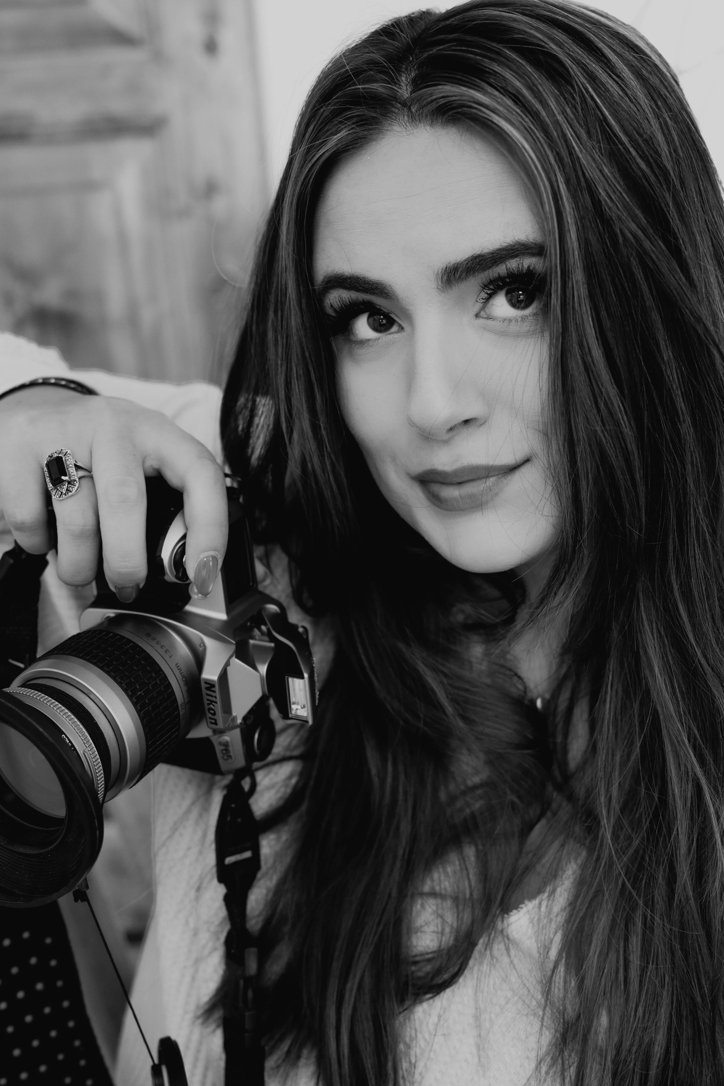 Black and white photo of a woman with long hair holding a camera.