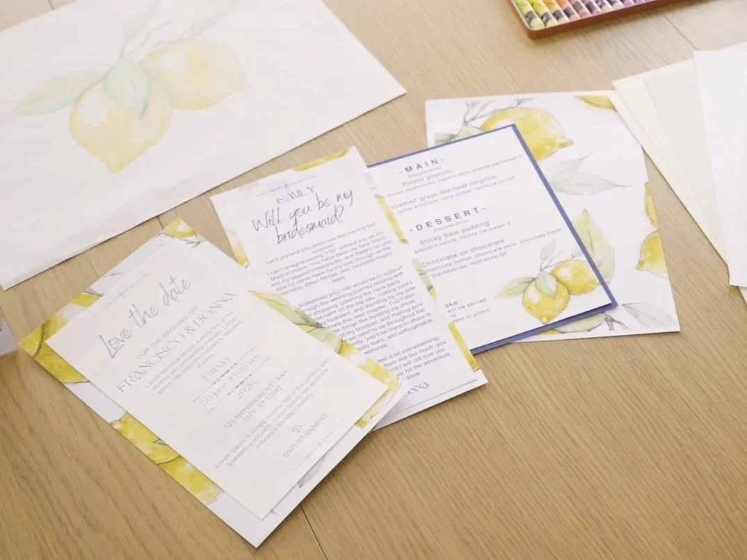 Wedding invitation and RSVP cards on a wooden table with lemon watercolor designs.