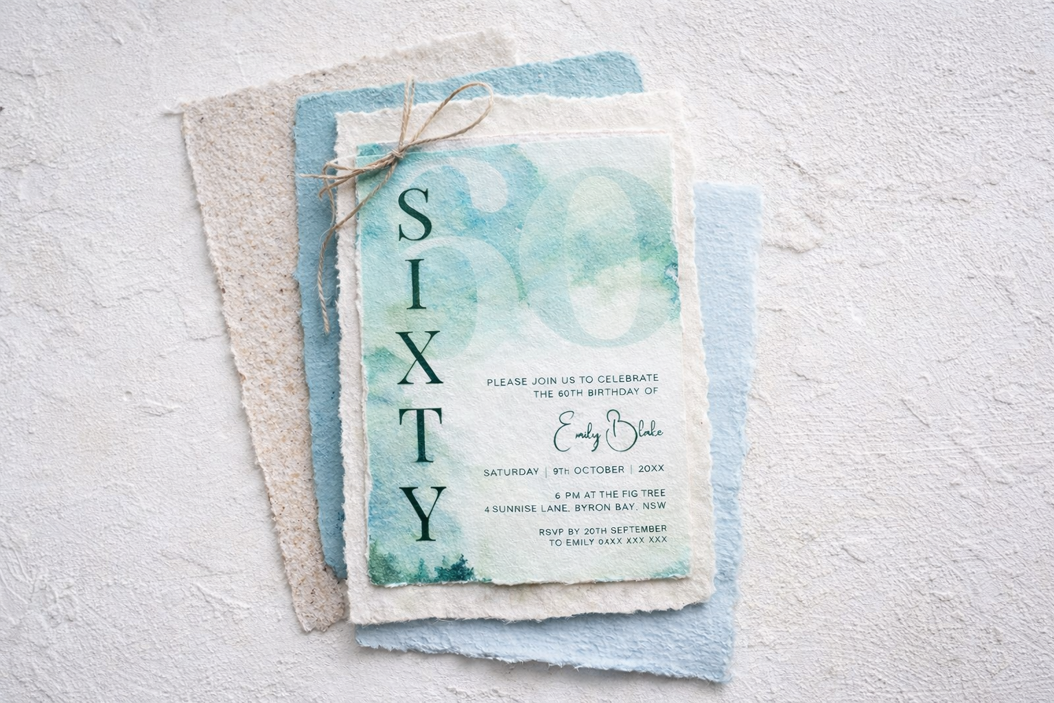 Watercolor birthday invitation card with blue and green hues, layered on textured paper, featuring details of a 60th birthday celebration for Emily Blake with date, time, and location.