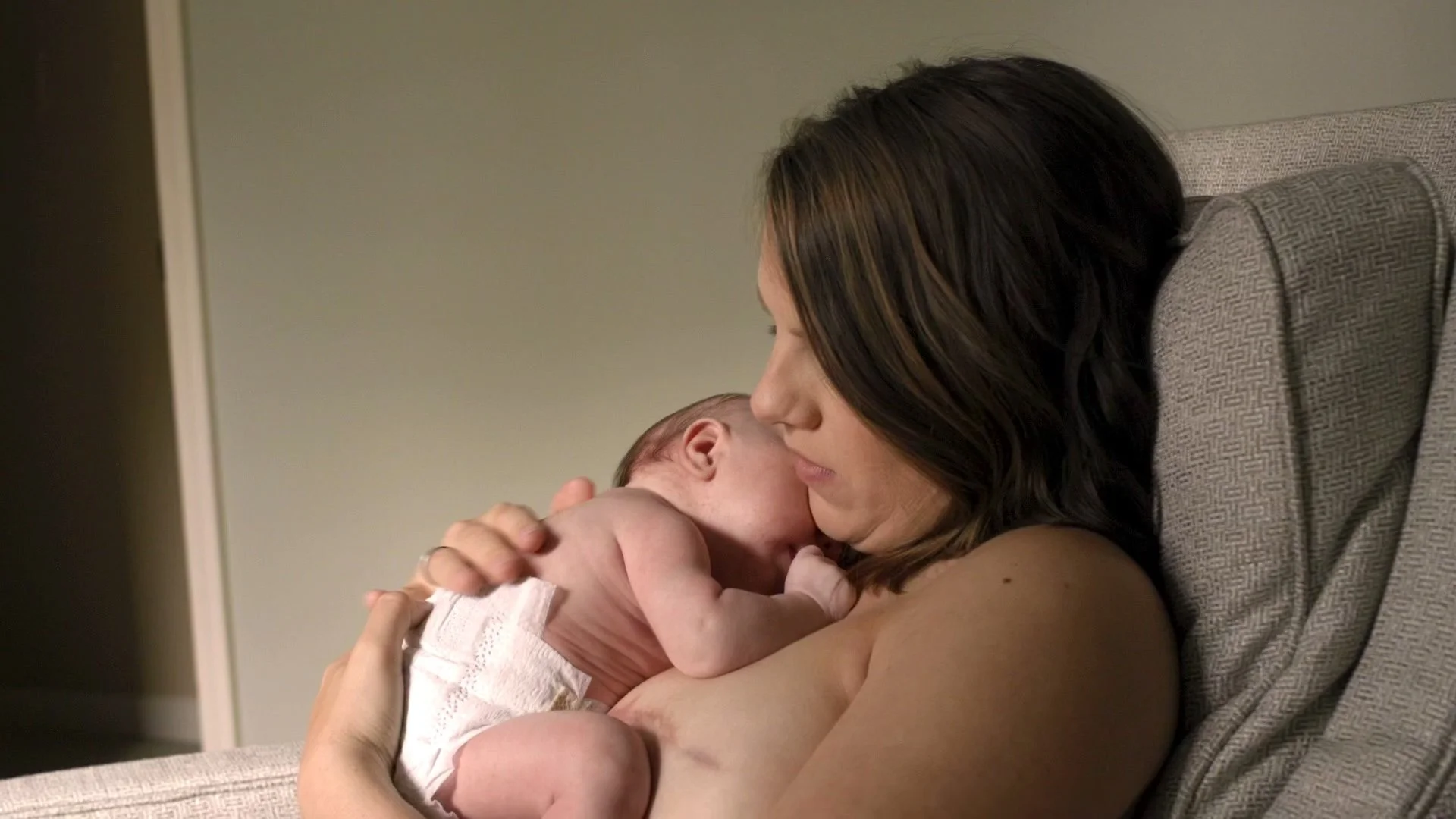 Lorelei Colbert hugs her newborn baby skin to skin. Her mastectomy scars visible.