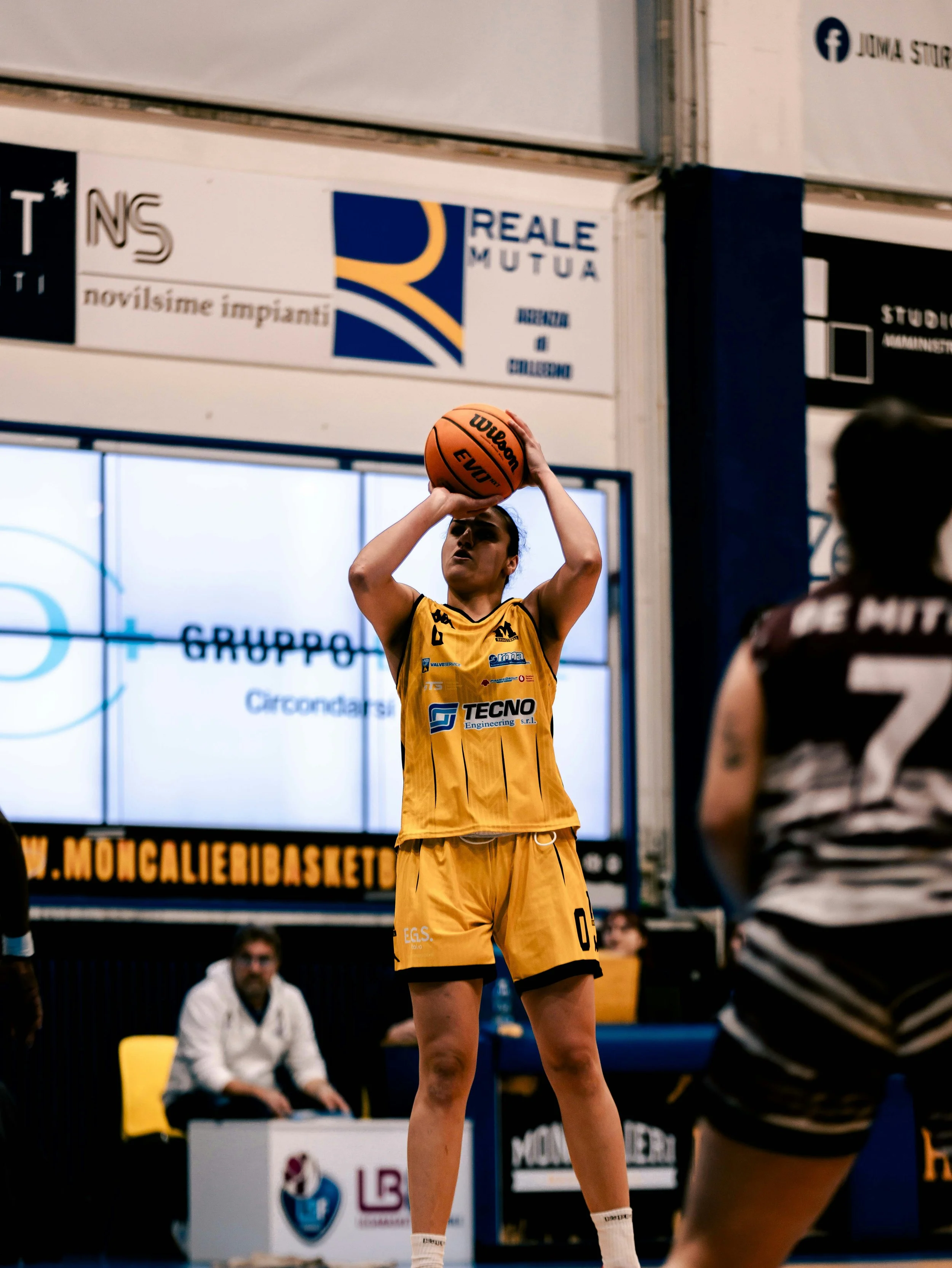 A female basketball player in a yellow uniform preparing to shoot a free throw during a game.