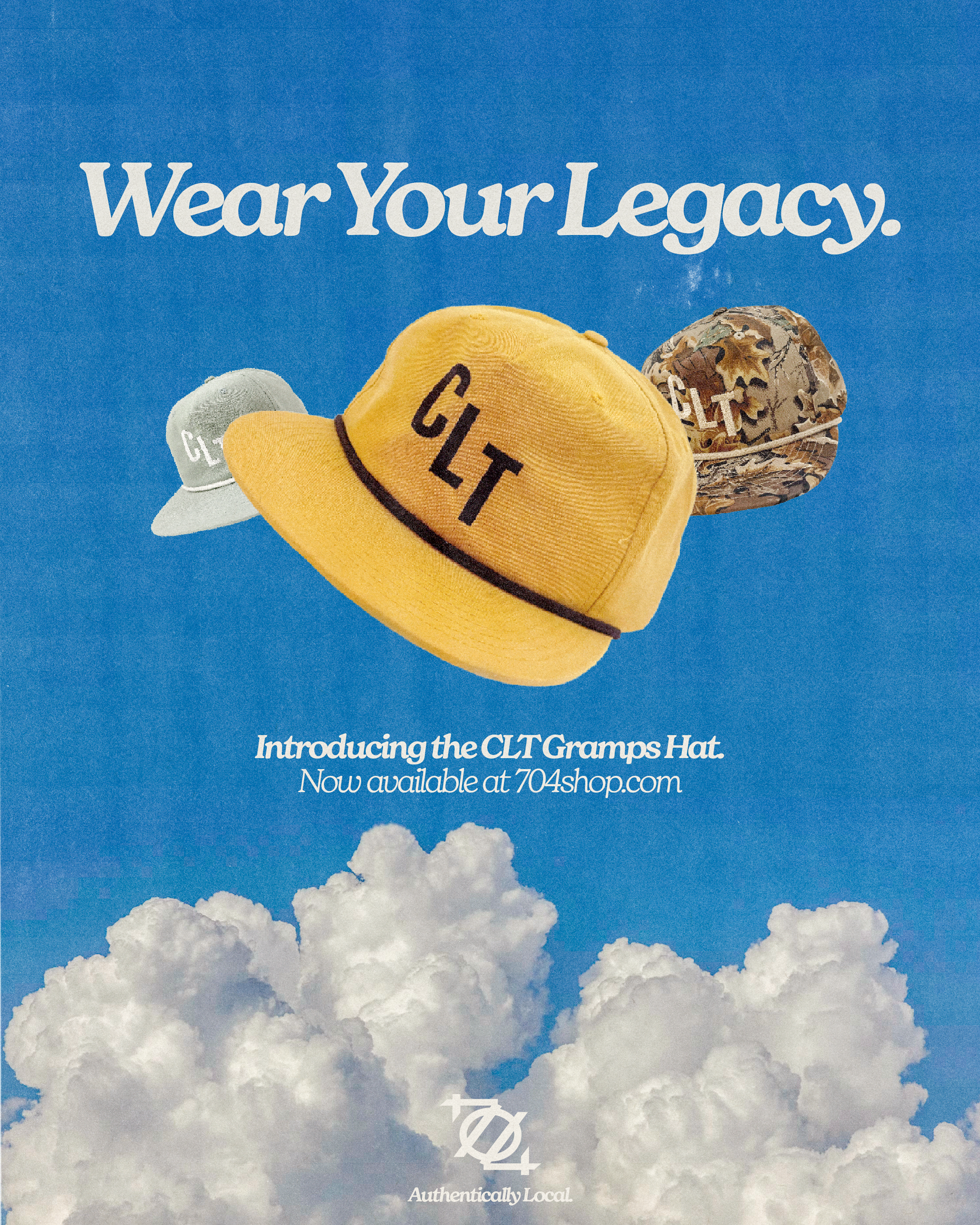 Sky filled with fluffy white clouds and a bright blue background, advertising the CLT Gramps Hat with text: 'Wear Your Legacy,' and indicating it is available at 704Shop.com, with the tagline 'Authentically Local.'