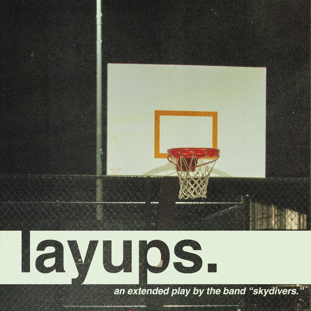 A basketball hoop on a dark outdoor court at night with a billboard or sign beneath it displaying the word 'layups.' in large bold letters, with the subtitle 'an extended play by the band "skydivers."'.