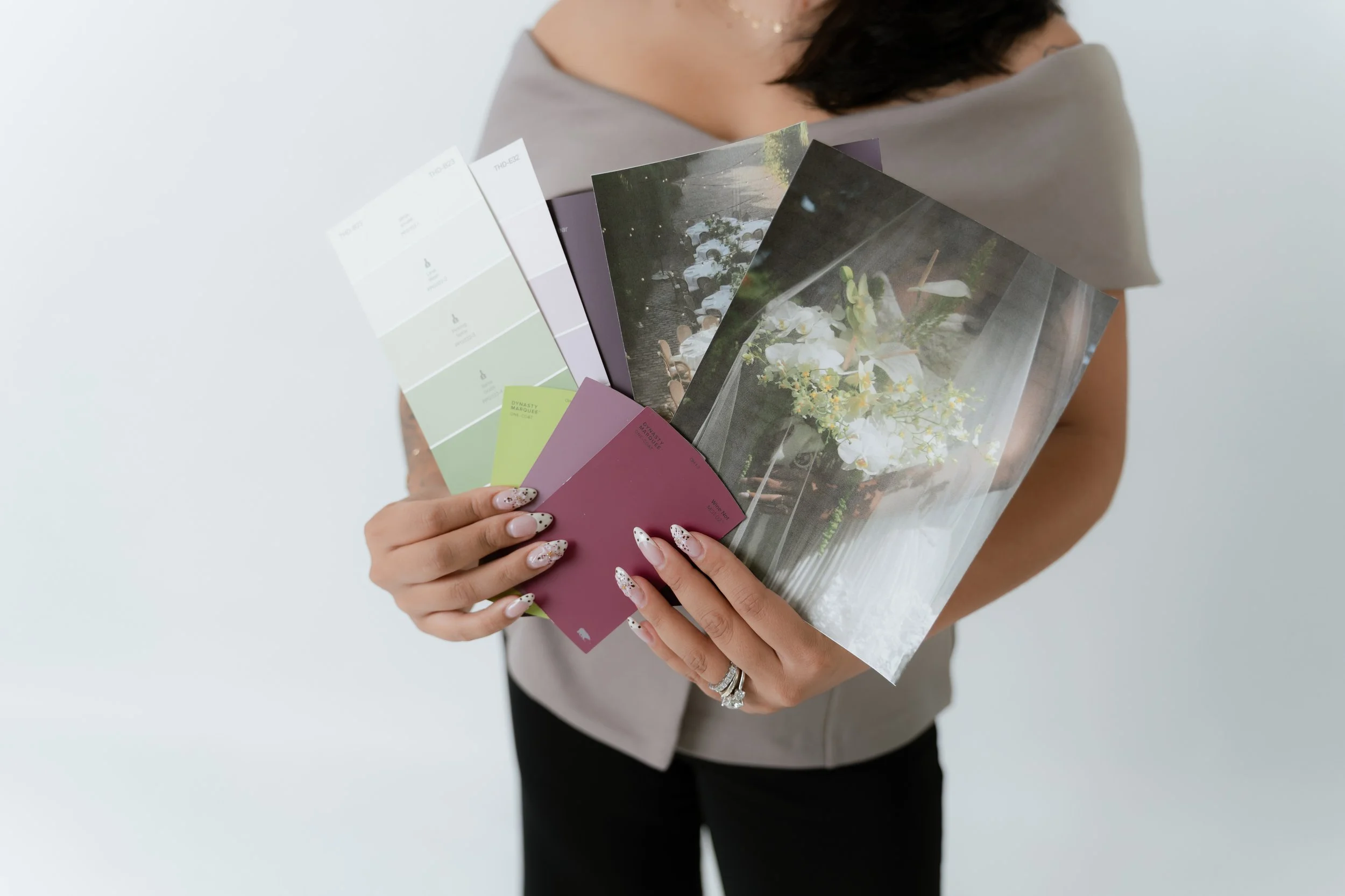 A person holding several printed photographs and color swatches with a white background.