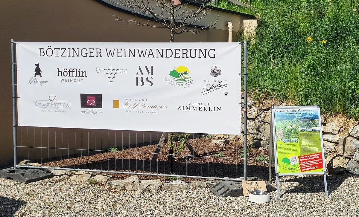 Ein Banner für die Bötzinger Weinwanderung mit verschiedenen Weingütern und Logos, daneben ein Informationsschild über die Region Endhale.