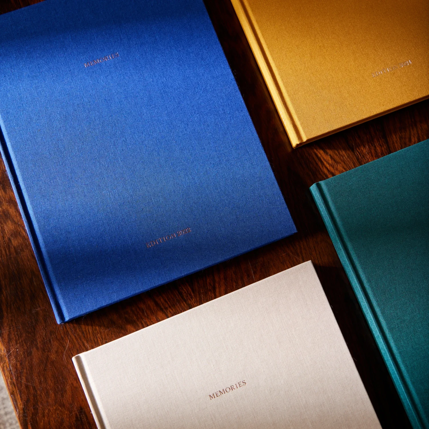 Livres de souvenirs de différentes couleurs sur une table en bois.