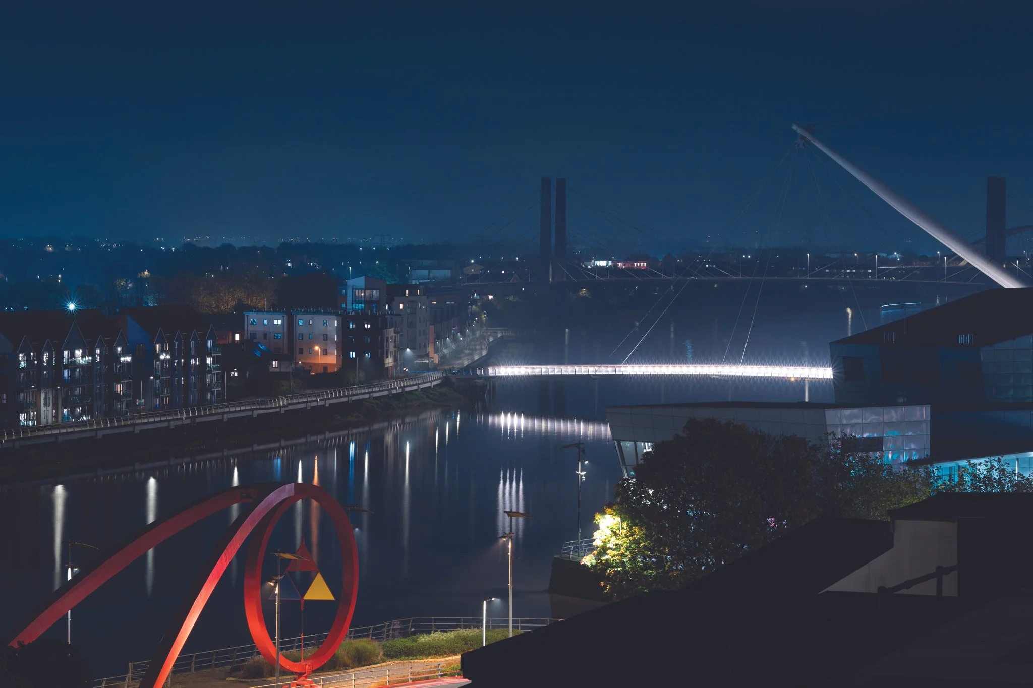 Use River at night, with the red wave structure, footbridge and Riverfront building