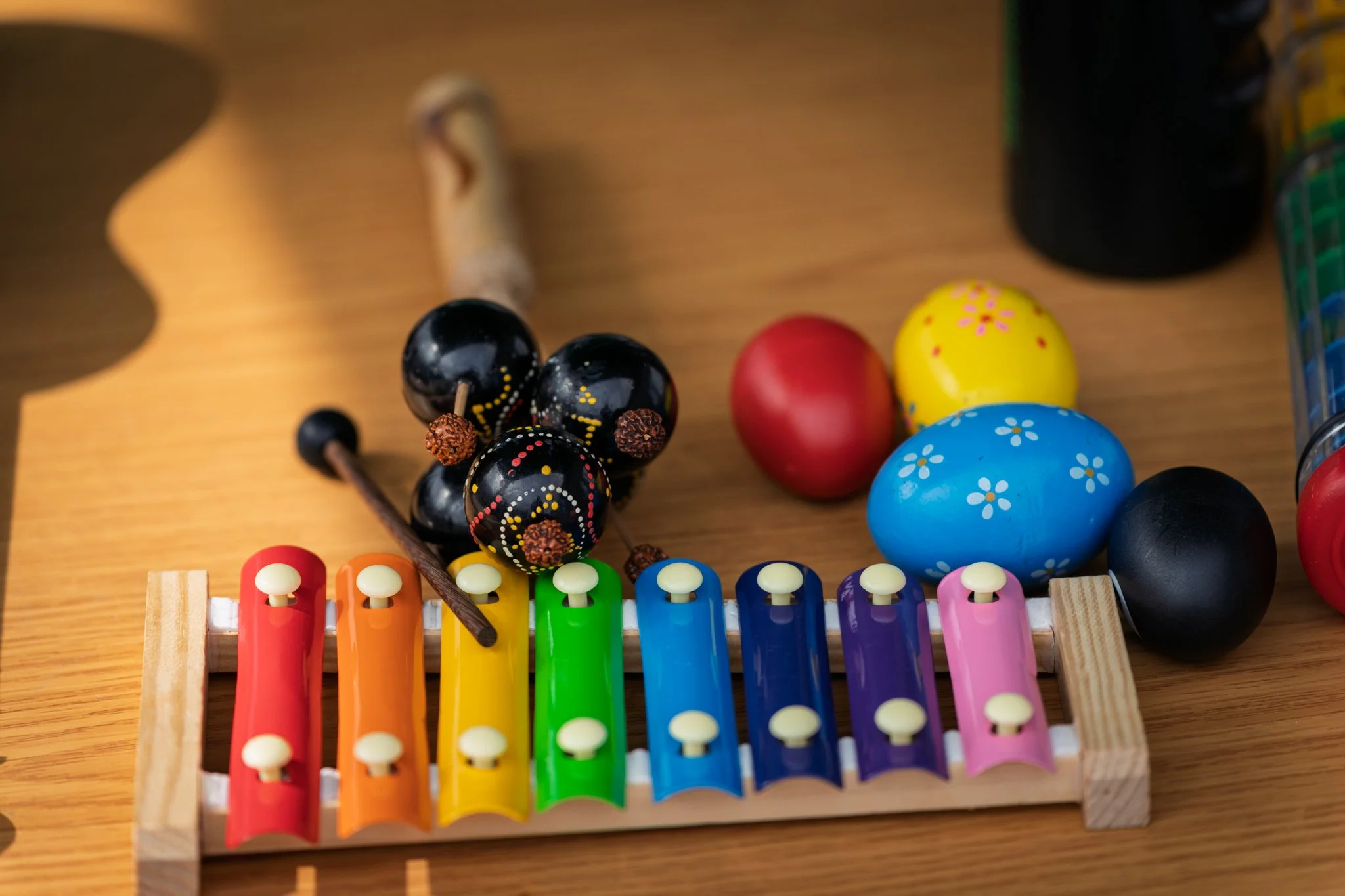 Colorful xylophone on a wooden surface, with painted Easter eggs and black beads on a string nearby.