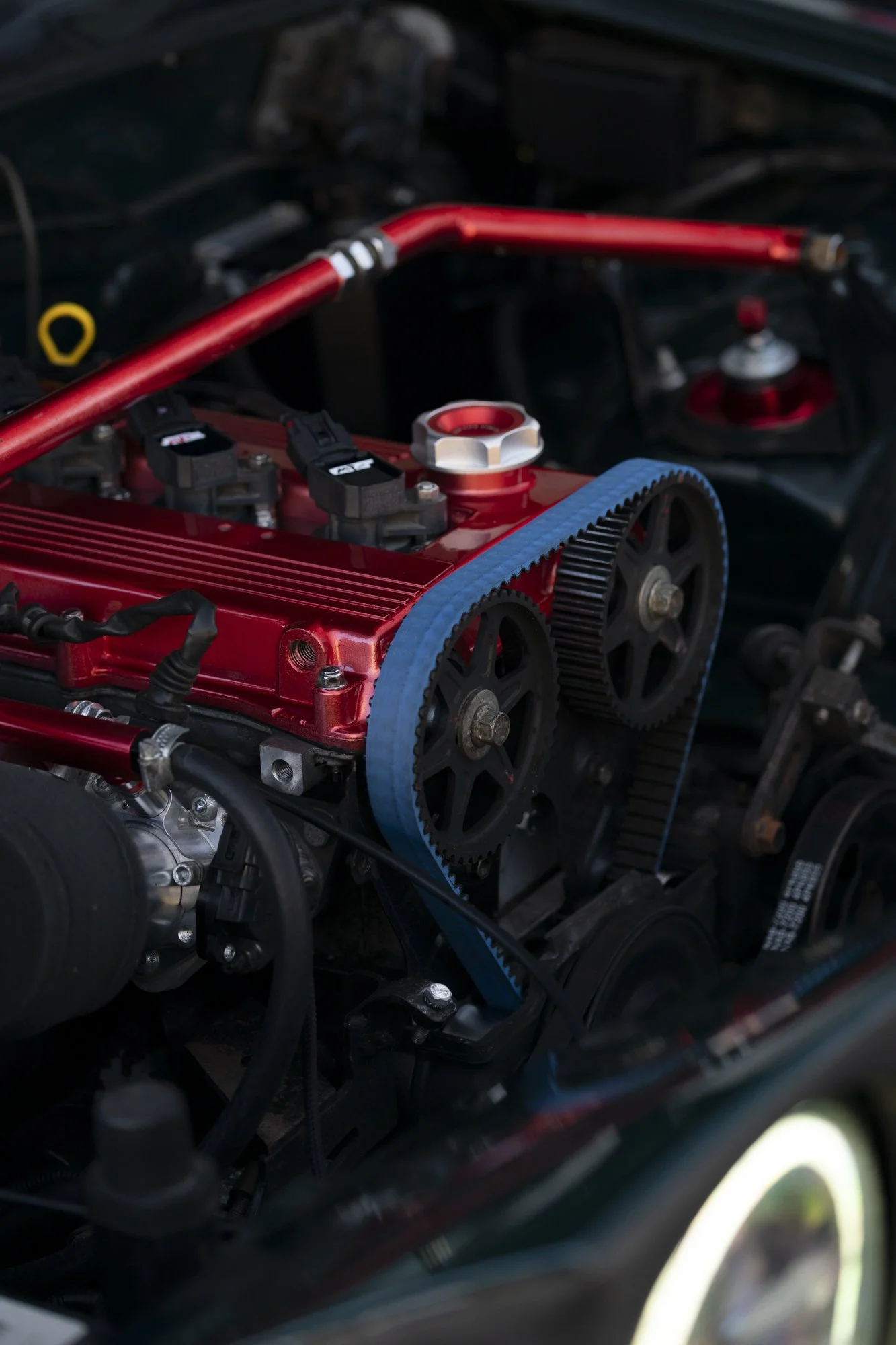 Close-up of a car engine with red accents, a blue timing belt, and black components.