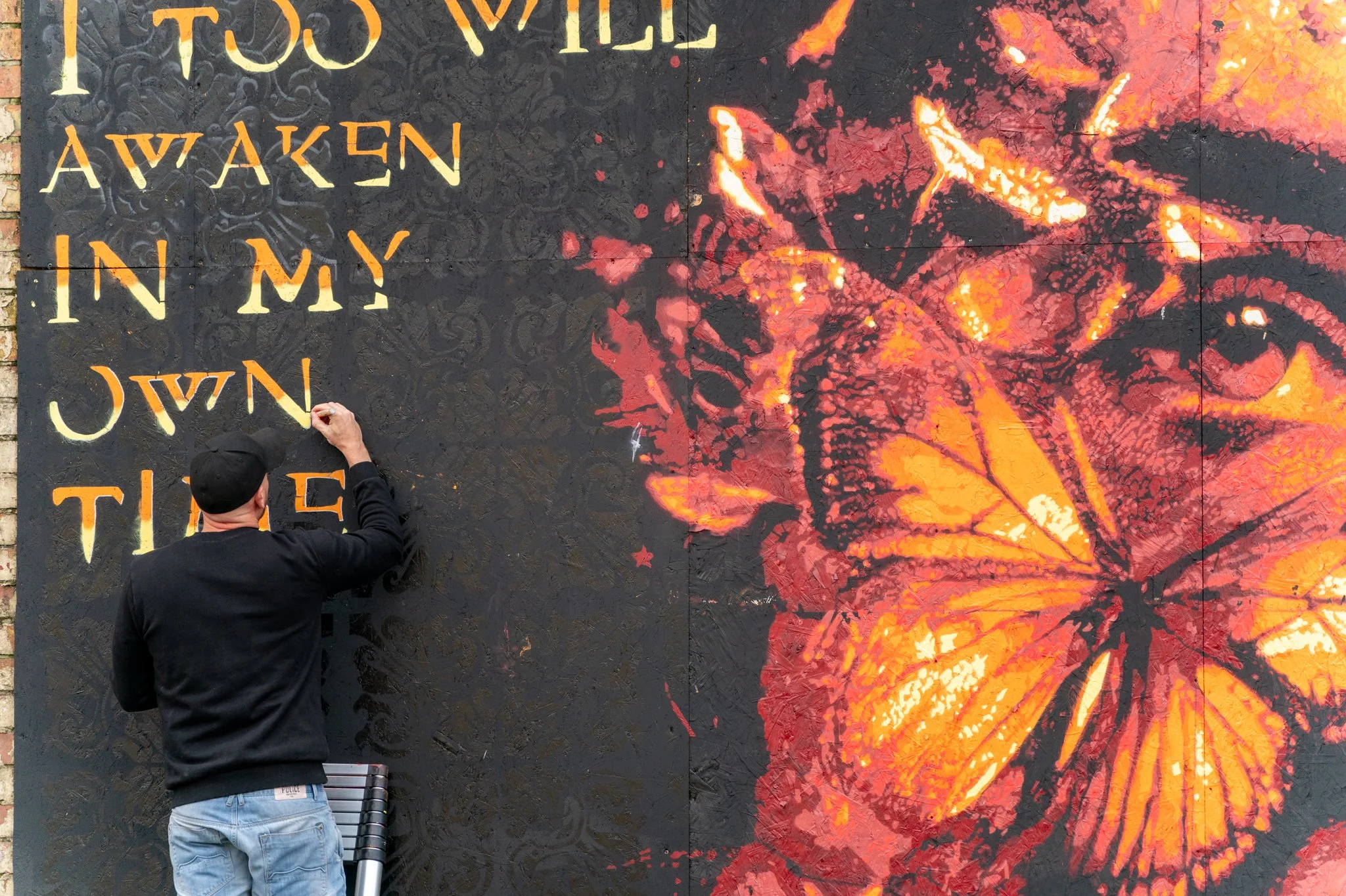 Artist painting on a wall, using yellow and orange paint - Full colour festival