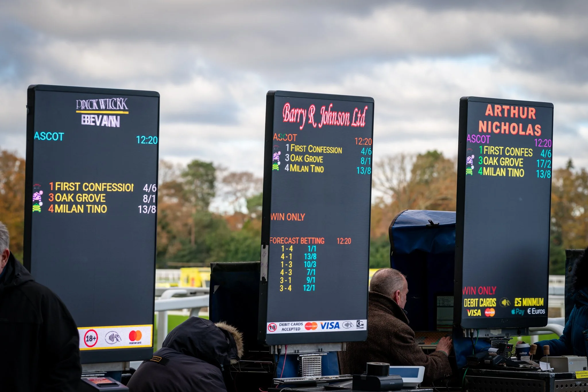 Digital betting screens at a horse racing track showing betting odds and race information.