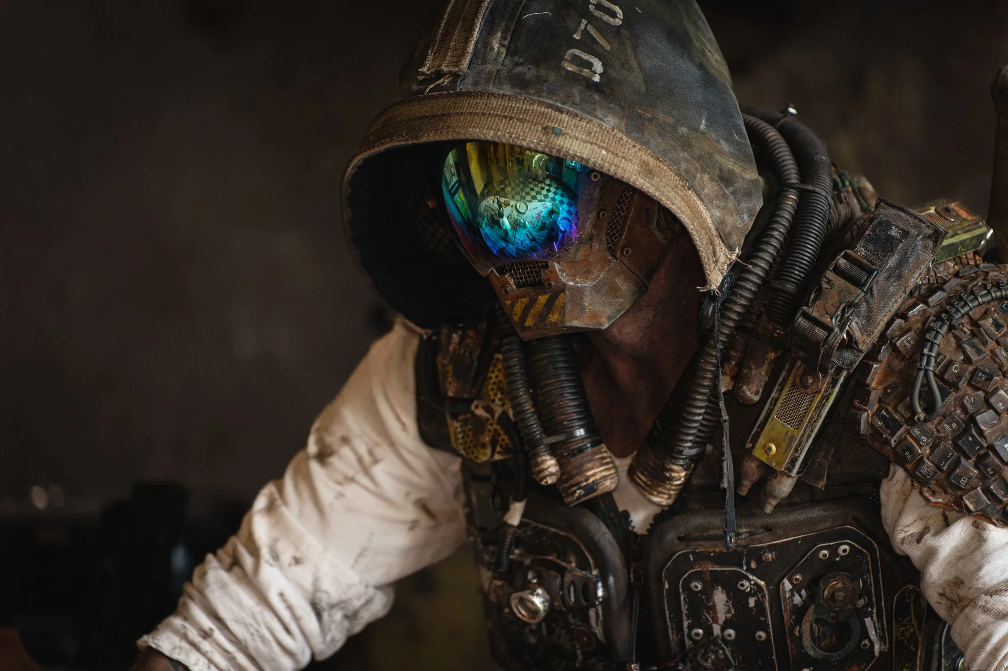 A person dressed in military or tactical gear, wearing a camouflage helmet with a visor reflecting a checkered floor and various objects, indicating a possibly futuristic or combat setting.