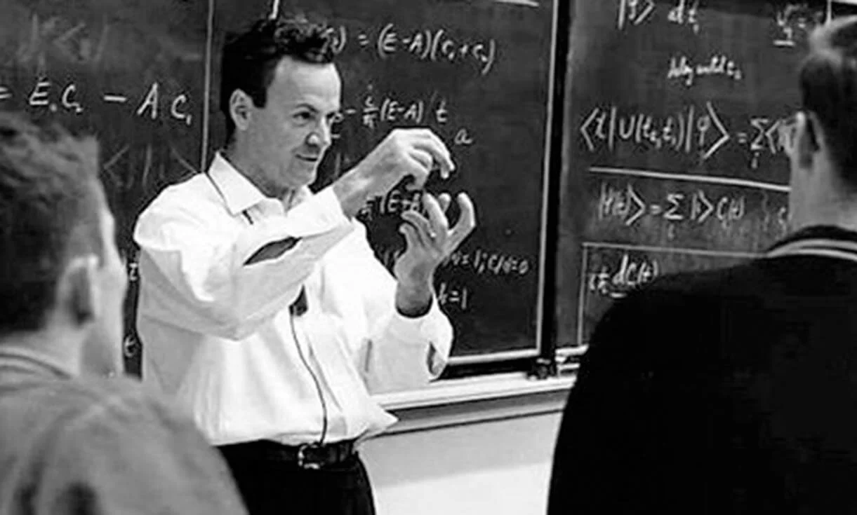 A male professor standing in front of a blackboard filled with advanced mathematical and scientific equations, teaching a class of students in a classroom.