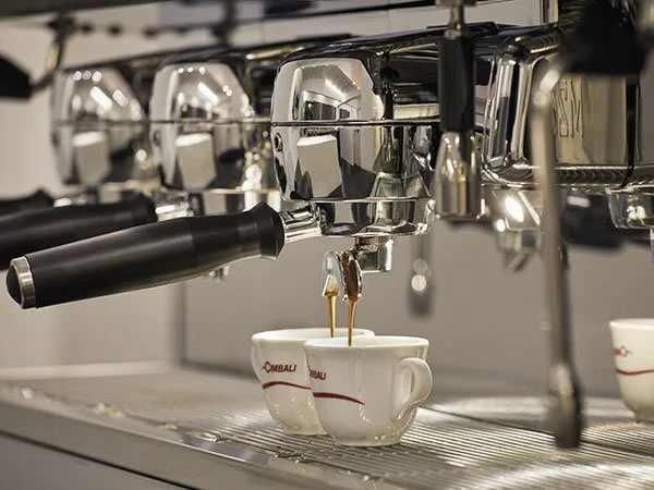 Espresso machine brewing coffee into two white cups.