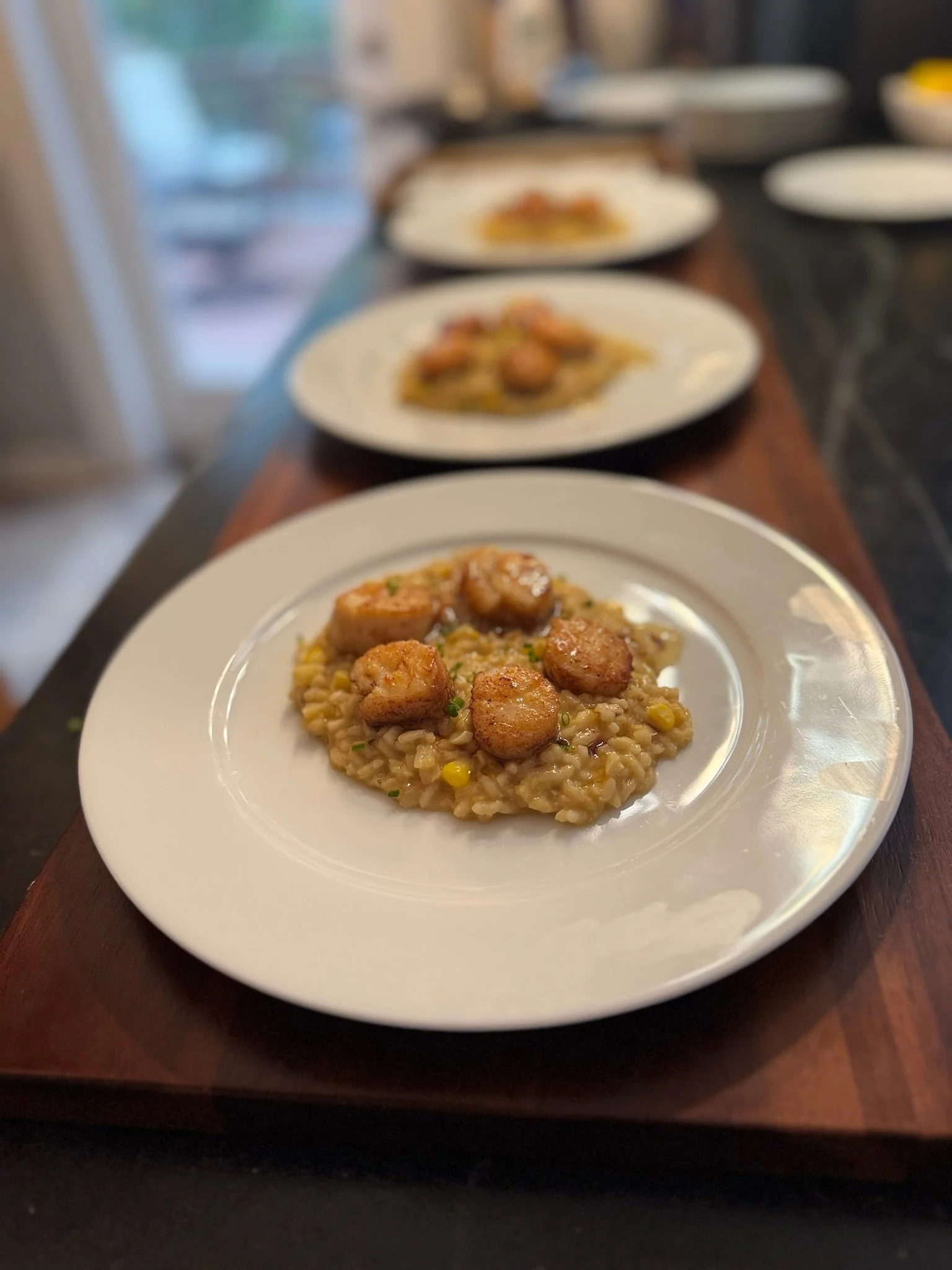 Seared scallops served over creamy corn risotto by Chef Lizzie