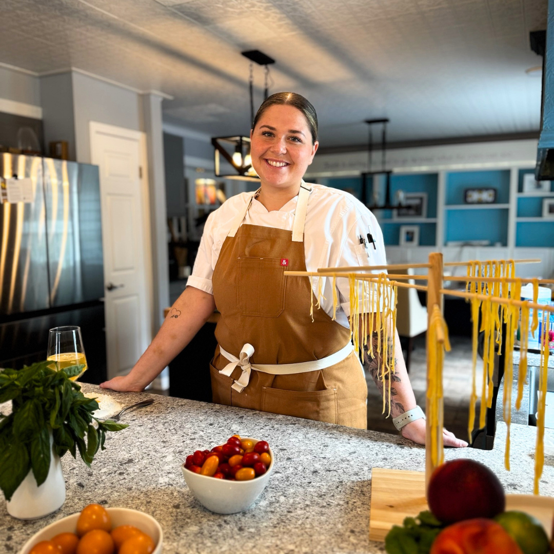 Chef Lizzie making fresh pasta for a Kitchen Party with tomatoes, lemons and seasonal ingredients