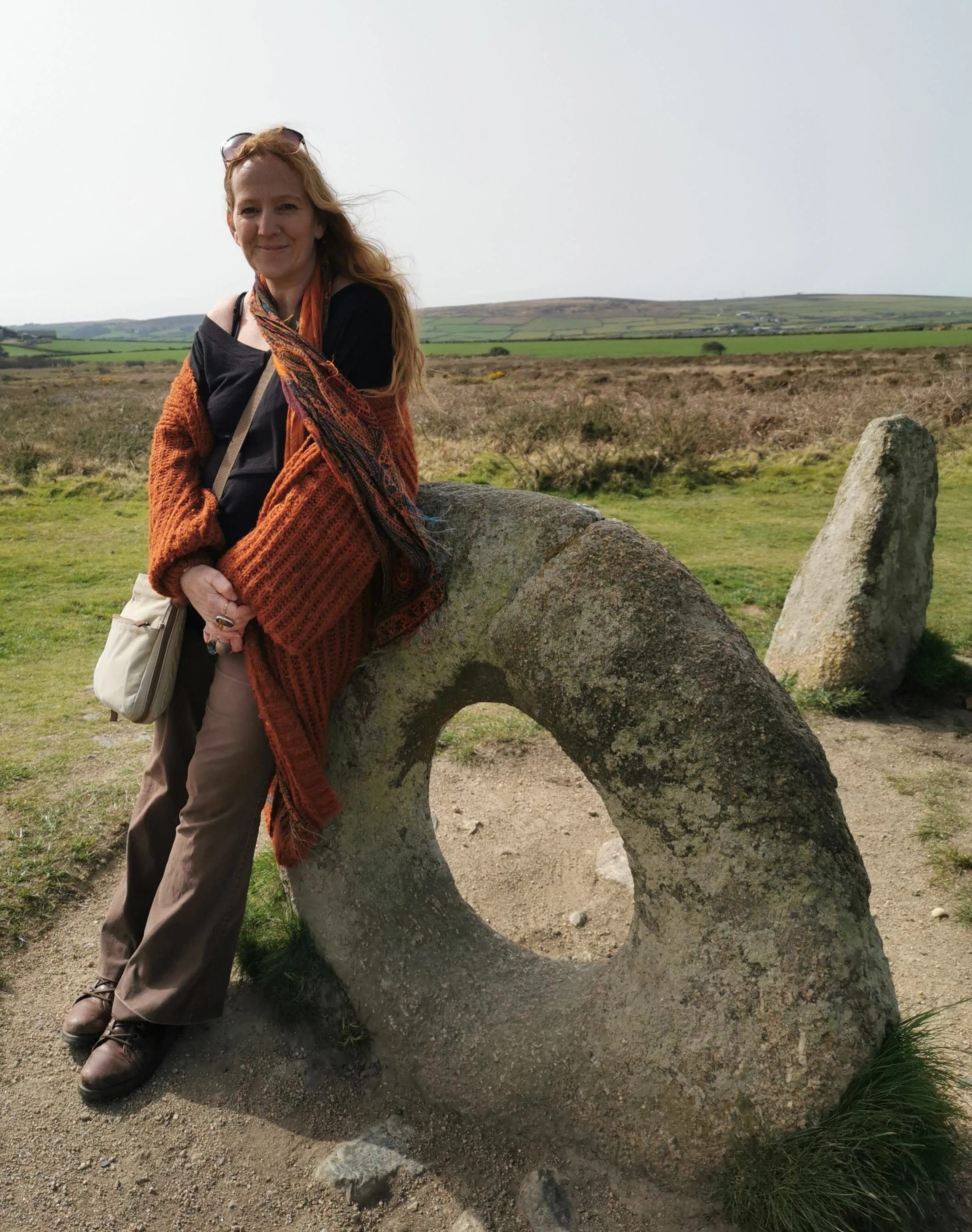 Cornwall artist Shelly Cook beside an ancient holed stone in the Cornish Landscape.