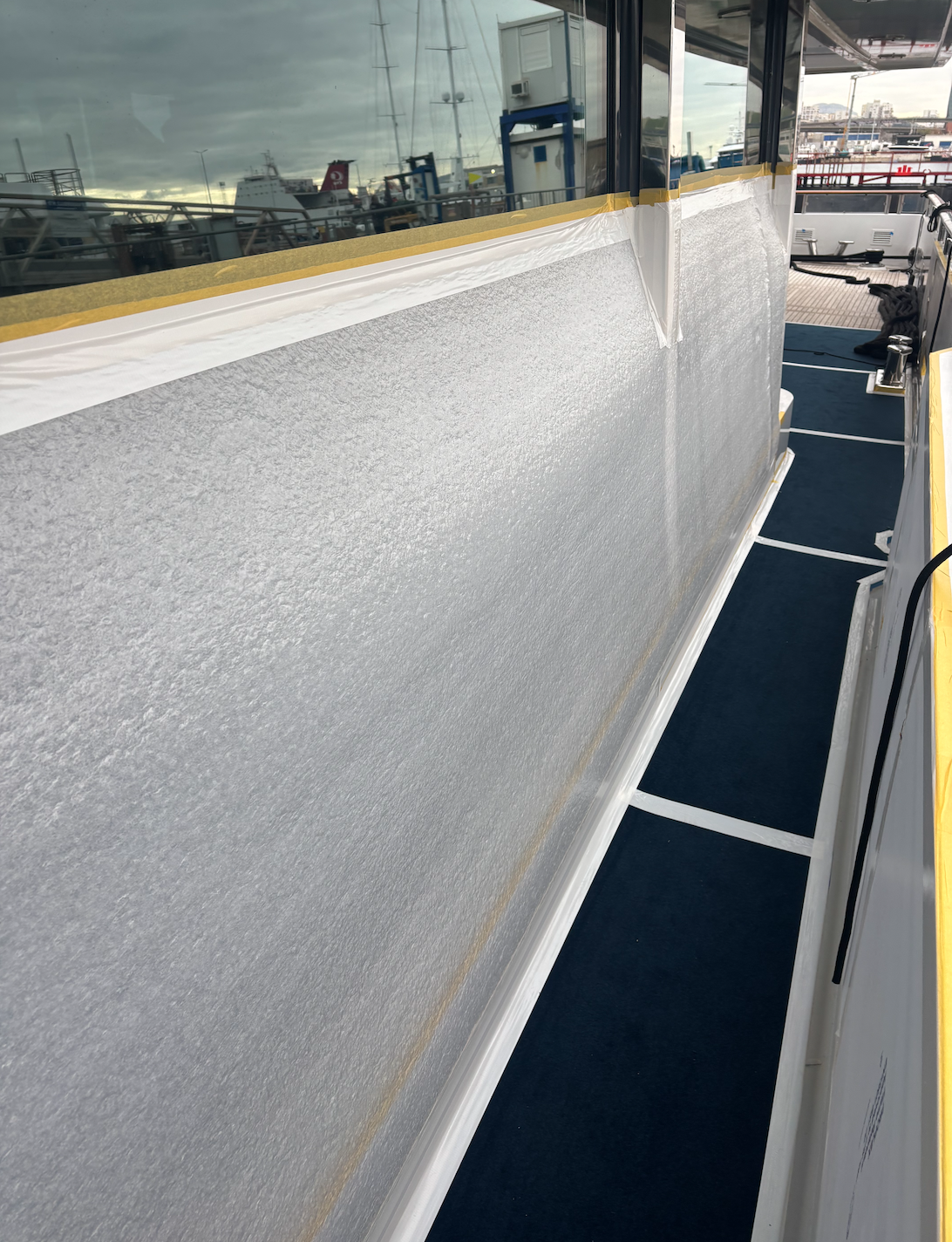 Surface du pont d'un bateau en cours de rénovation avec de la peinture ou un revêtement en cours d'application.