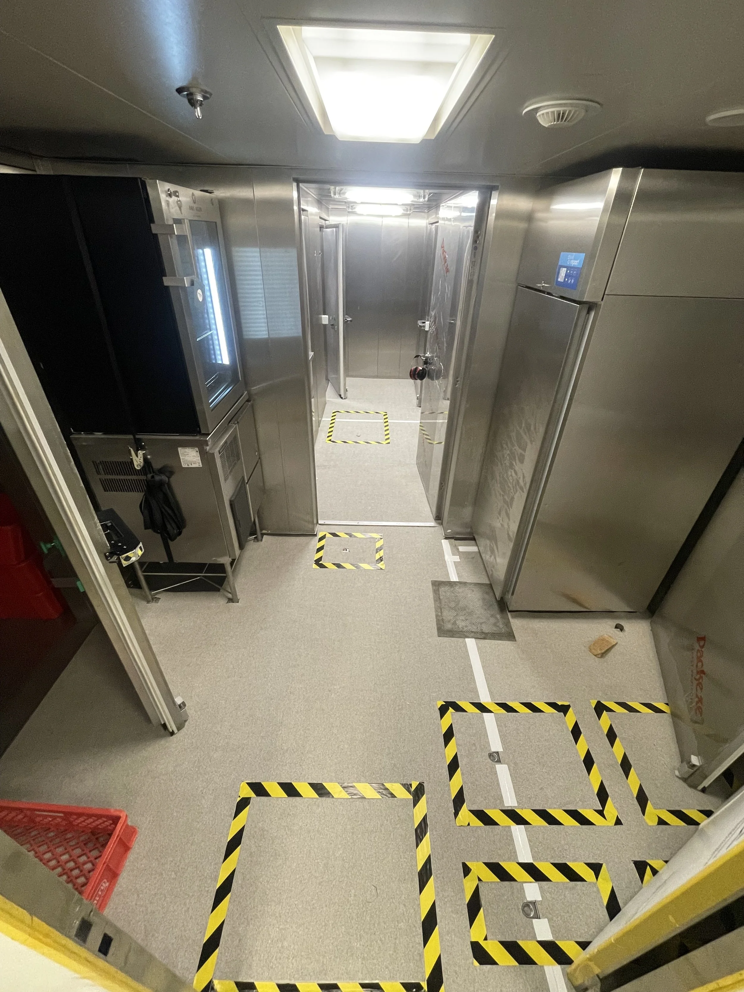 Salle réfrigérée de yacht avec le sol couvert de moquette temporaire pour les différents travaux, avec du scotch jaune et noir autour des hatchs pour la sécurité.