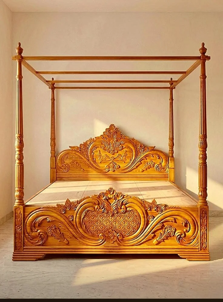 Wooden four-poster bed with ornate carvings on headboard and footboard in a well-lit room.