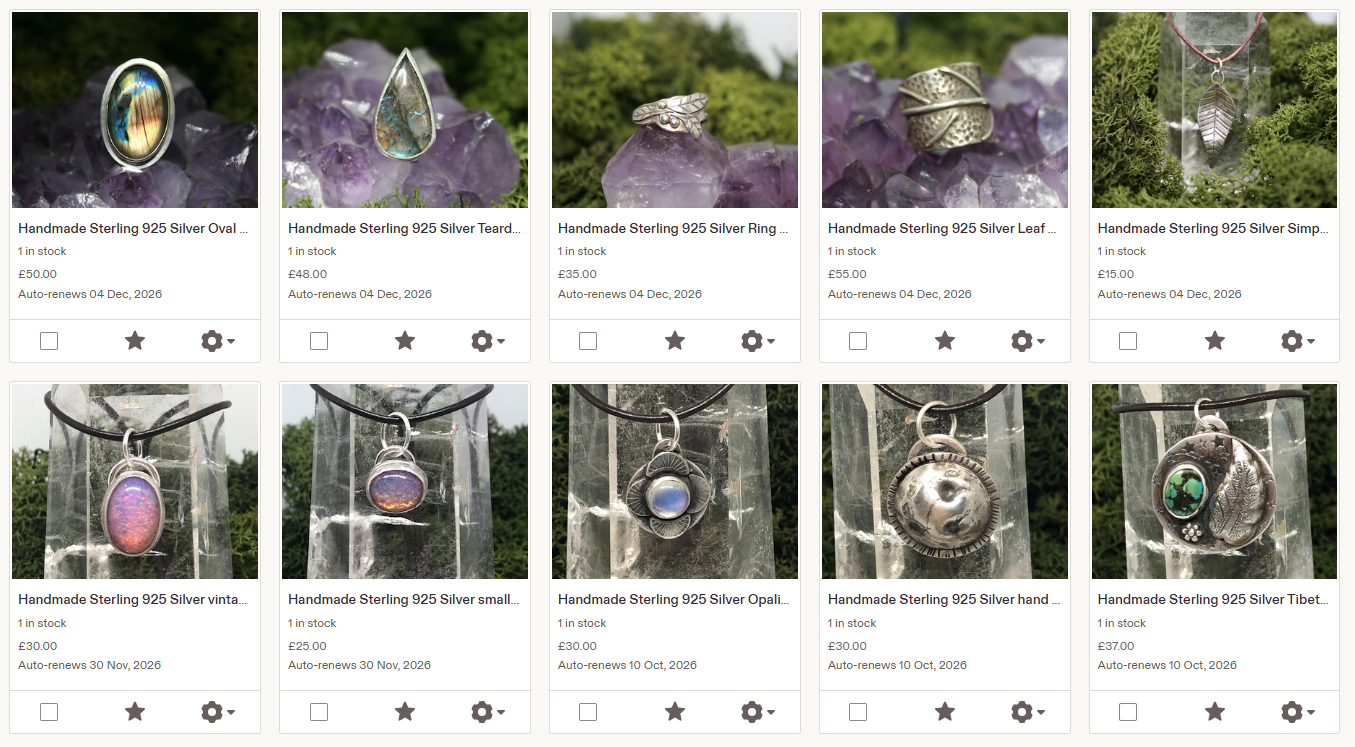 A collection of handmade sterling silver jewelry, including rings, necklaces, and pendants, featuring various stones and designs, displayed on gift boxes and greenery.