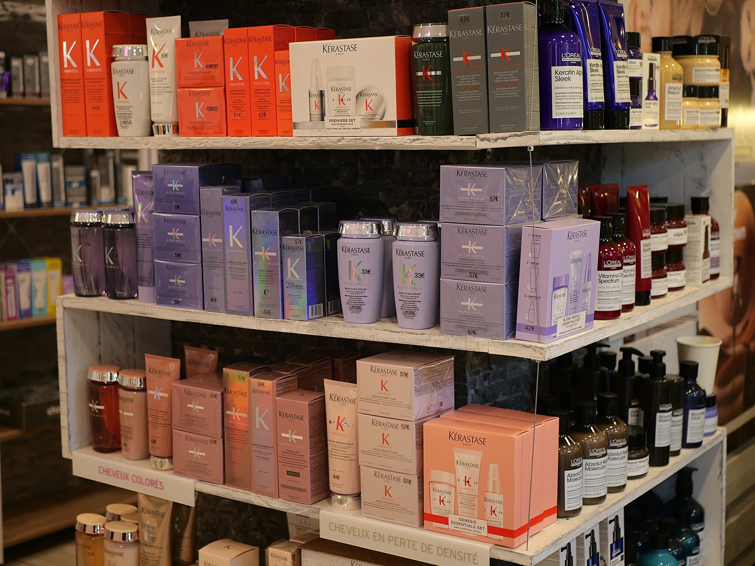 Étagère de produits capillaires de différentes marques, notamment Kérastase et L'Oréal, dans un magasin.