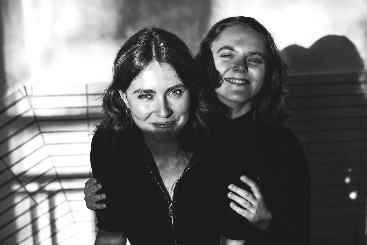 Two women smiling and hugging each other, in black and white photo.