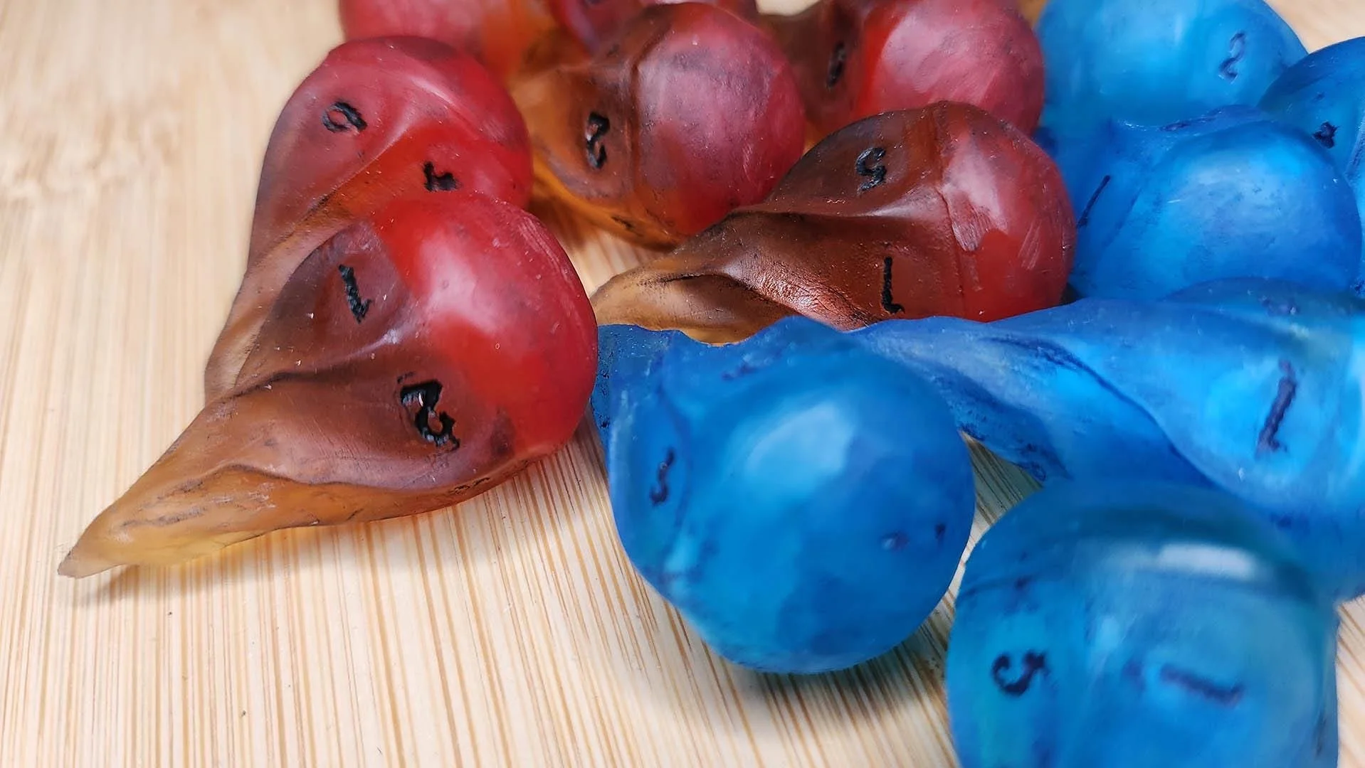 Detailed picture of the blue flame JoaraCrafts Fireball dnd Dice Set. 
In this picture you can see how the base of the fireball shape seems to have a flame-like effect that has been darkened with the same paint used to color the numbers of the dice i