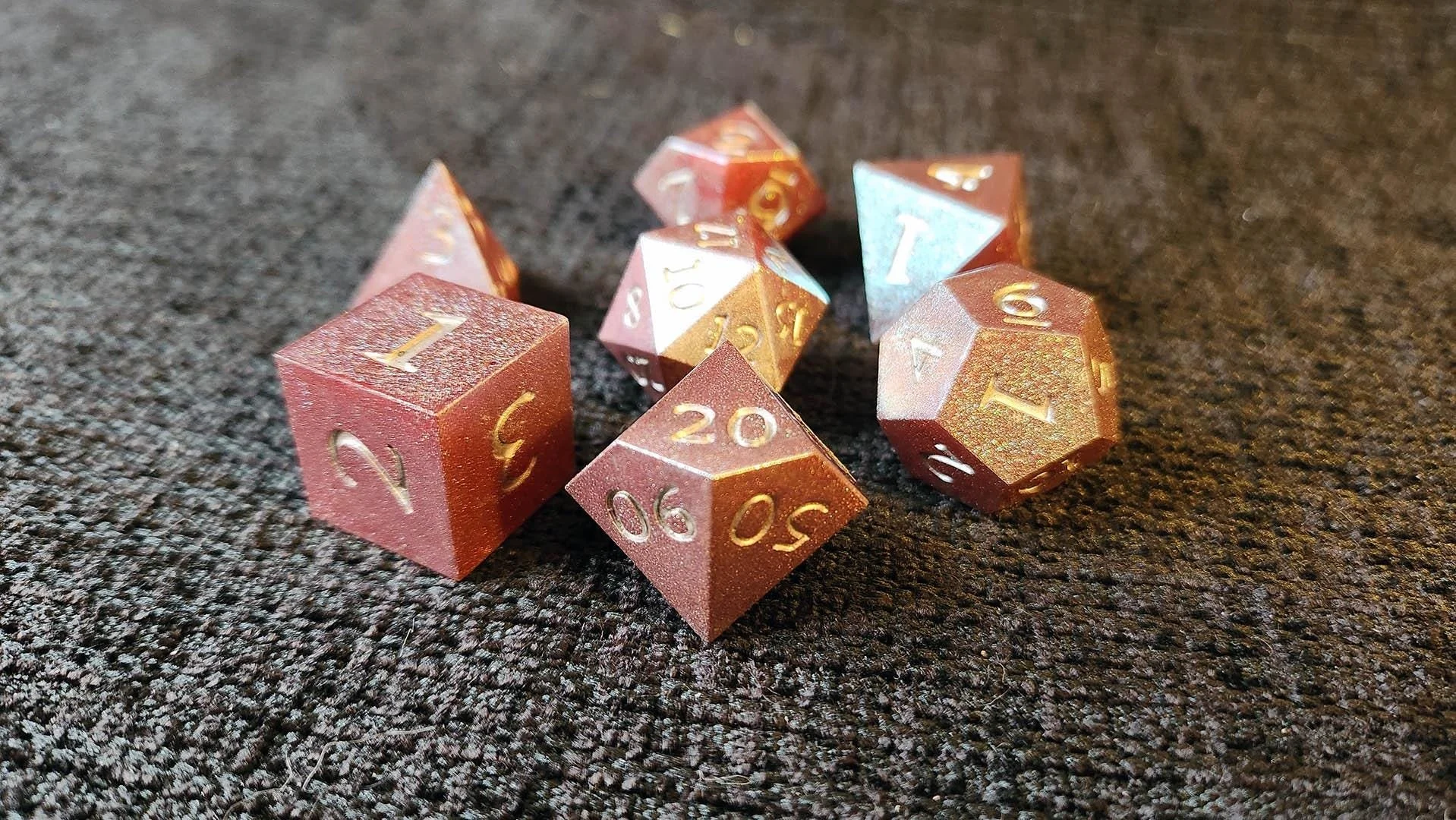 JoaraCrafts' Shimmering Twilight dnd dice set detail picture with the D6 in focus, the blue reflective specs over the dark red show part of the chameleon dice effect in this set. All dice are noticeably handcrafted.