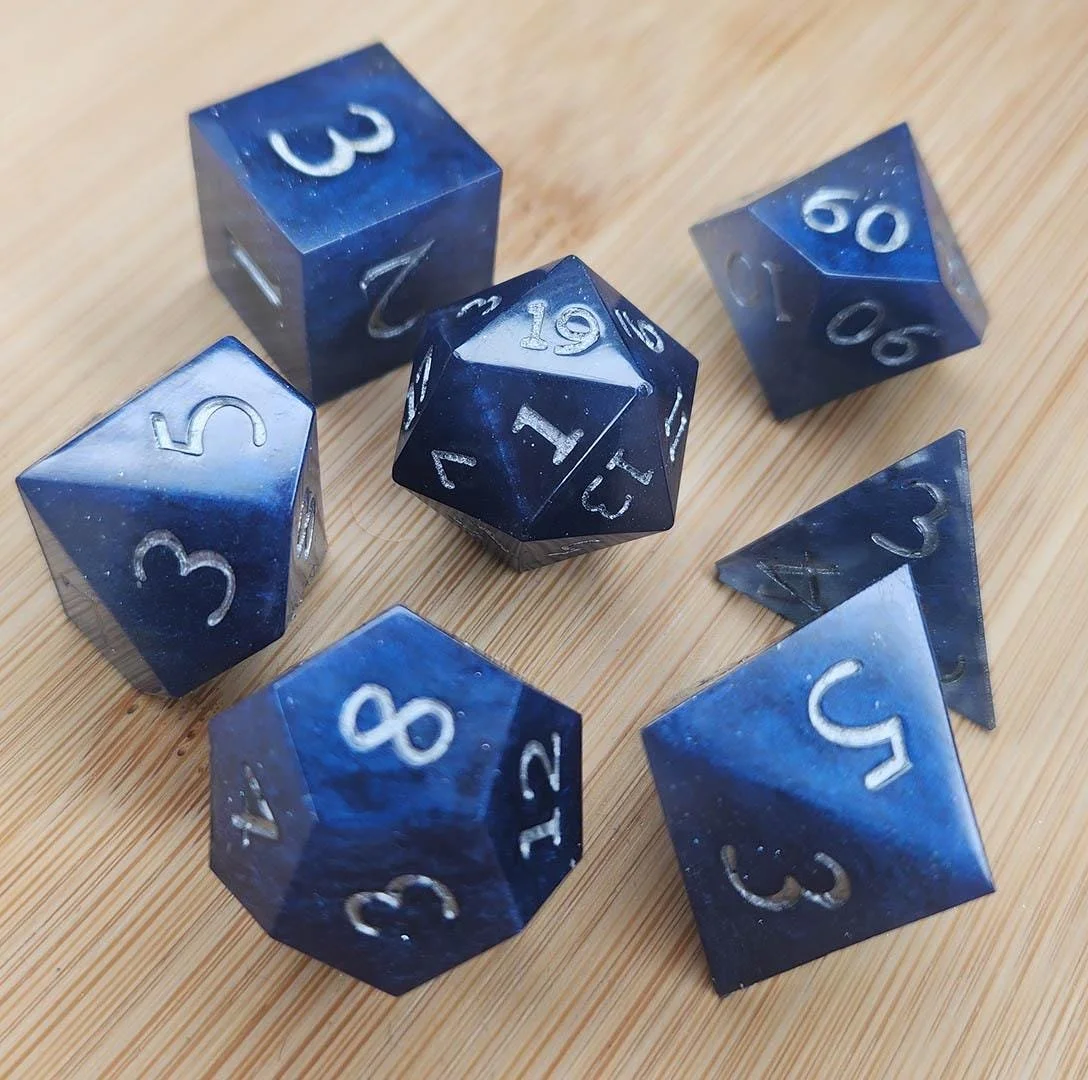Detailed photo of the silver number variant of the Night Sky dnd dice sets. In this picture you can see how shiny the dice are and you can see the cloudy effect more clearly.