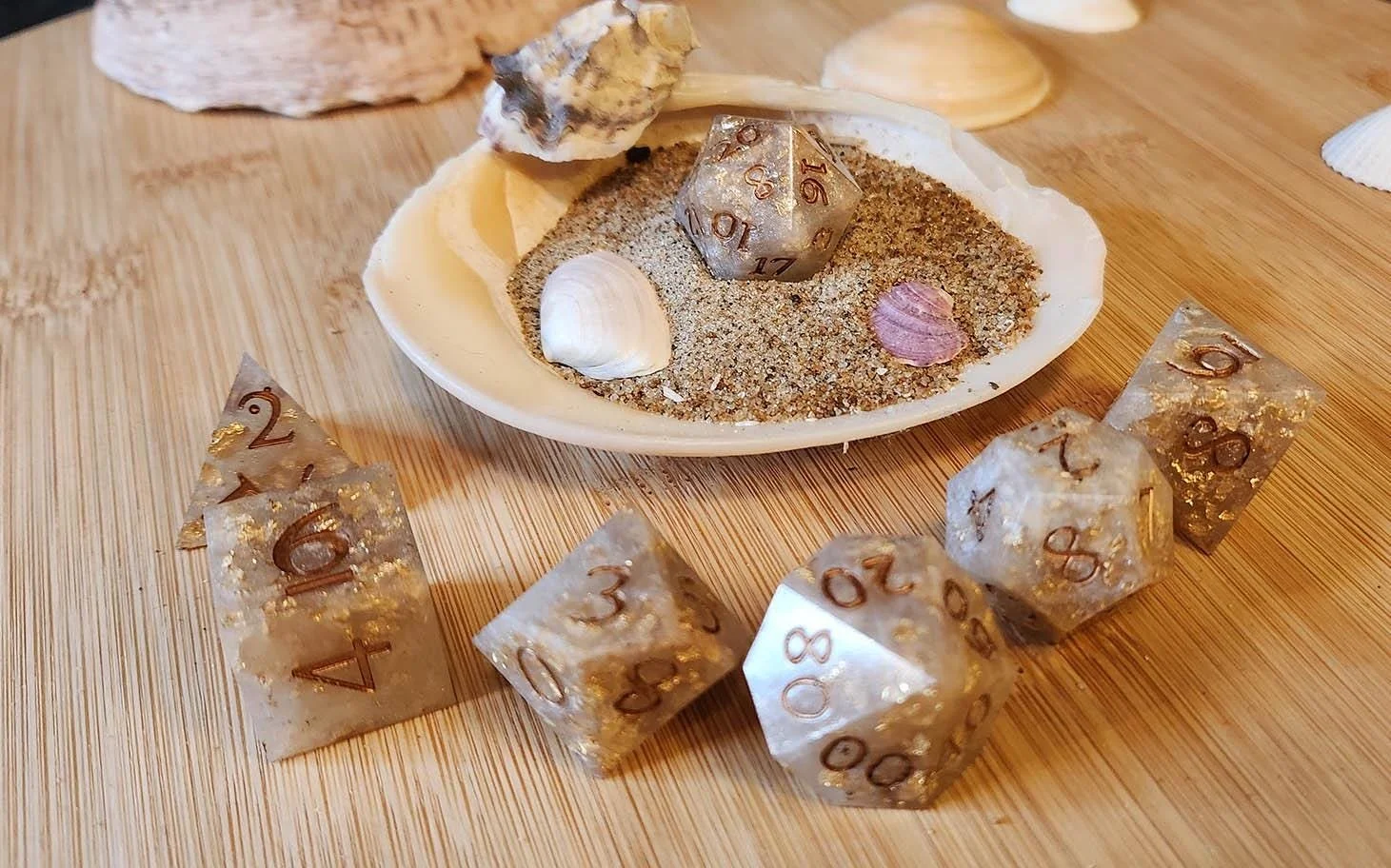Golden pearl white dice set within a large conch embedded in Swedish Scandinavian glittering sand.

This dice set gets the color through the use of a pearl white mica powder mixed with gold leaf, in the end the dice get a a beautiful pearl like opaqu