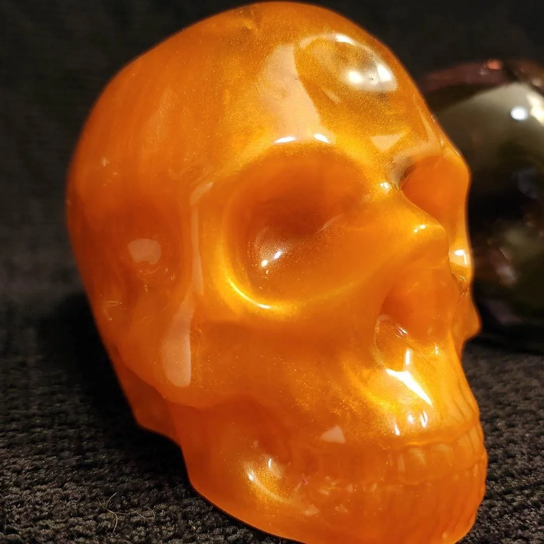 Detailed photo of a bright orange colored JoaraCrafts Anti-Waste Decorative Skull with orange and black resin scraps
