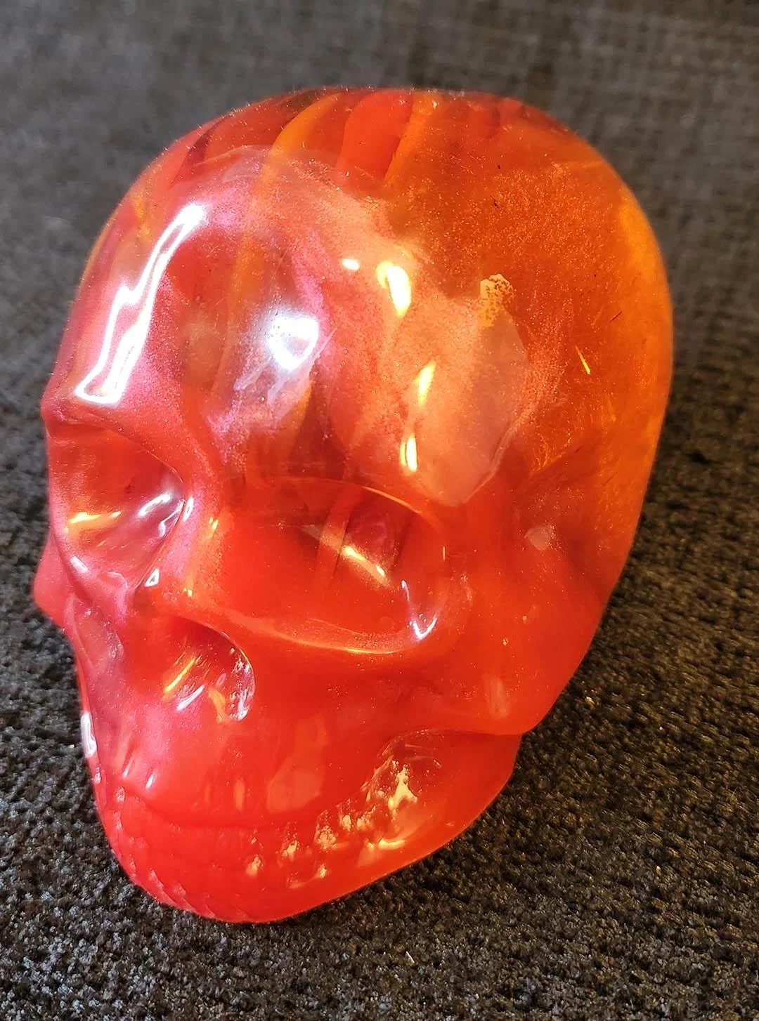 Detailed photo of a bright red colored JoaraCrafts Anti-Waste Decorative Skull with red and orange resin scraps
