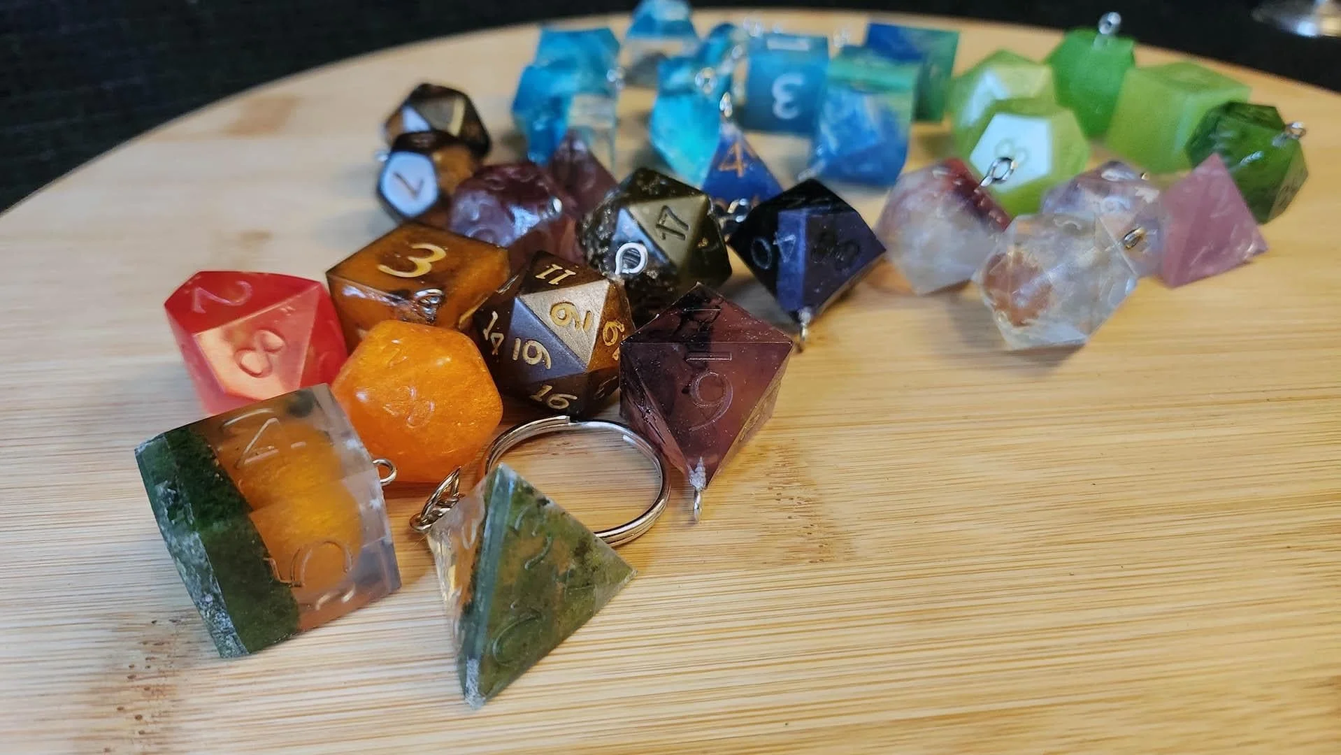 An example of a JoaraCrafts Anti-Waste Dice Keychain alongside several other samples with a hook alone.