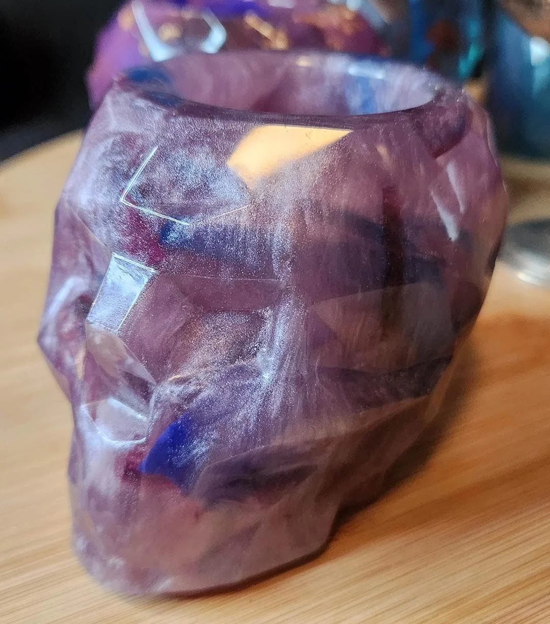 A detailed photo of one of the JoaraCrafts Anti-Waste Resin Geometric Skull Pen Holder. This skull is purple and with some darker purple accents. The photo is taken with wooden background.