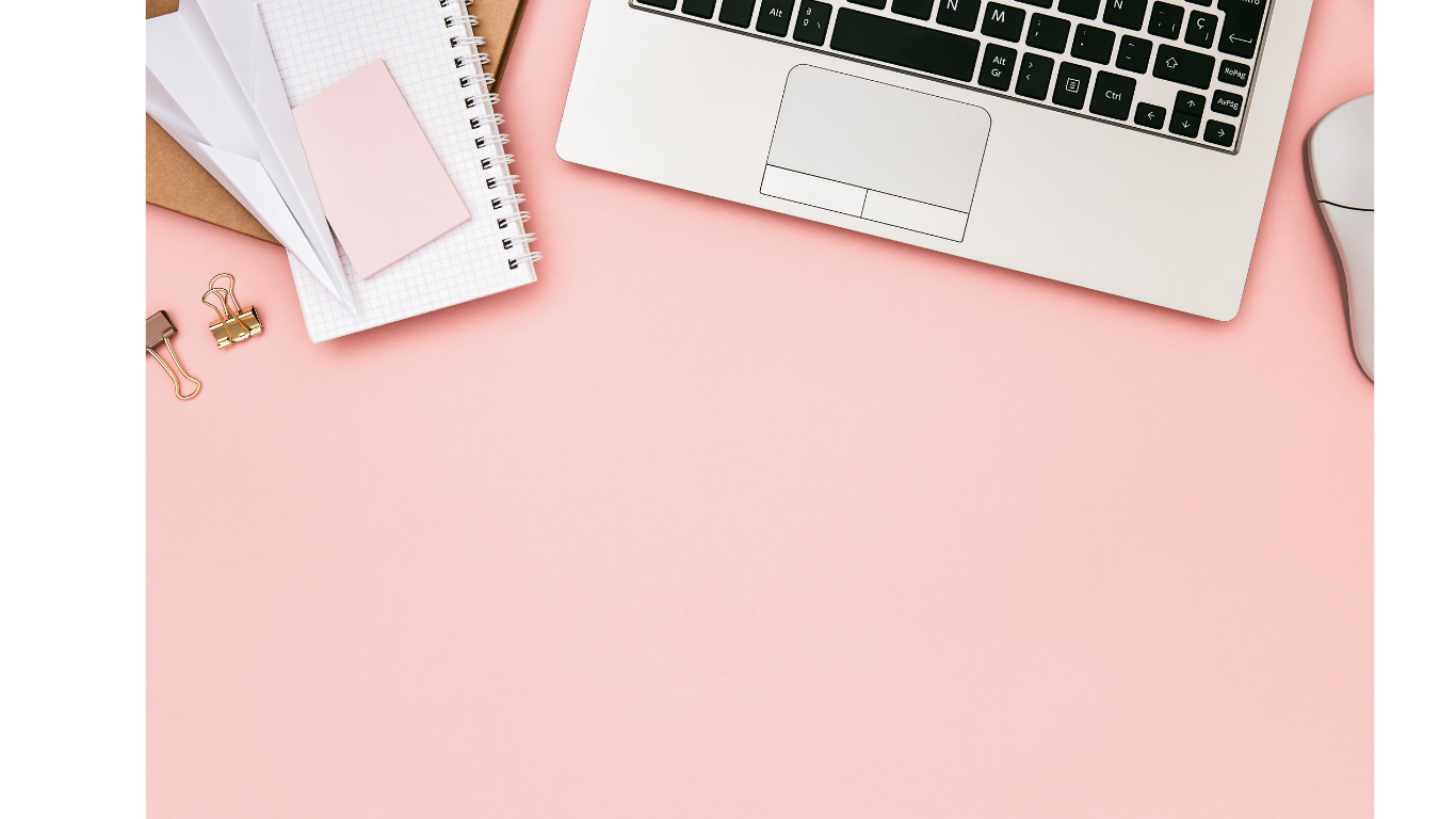 Top view of a workspace with a laptop, a white computer mouse, notebooks, and paperclips on a pink background.