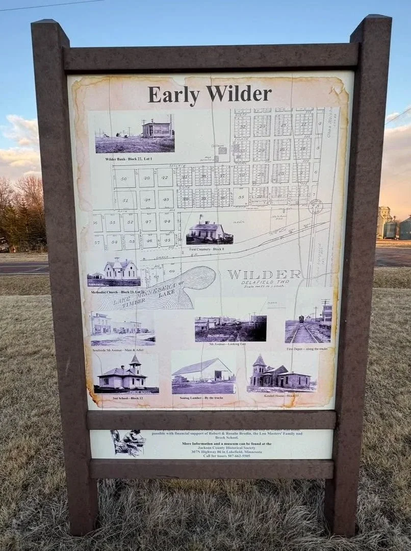 Historical informational sign about early Wilder, featuring old photographs of buildings, a map of the area, and descriptions of the community's history.