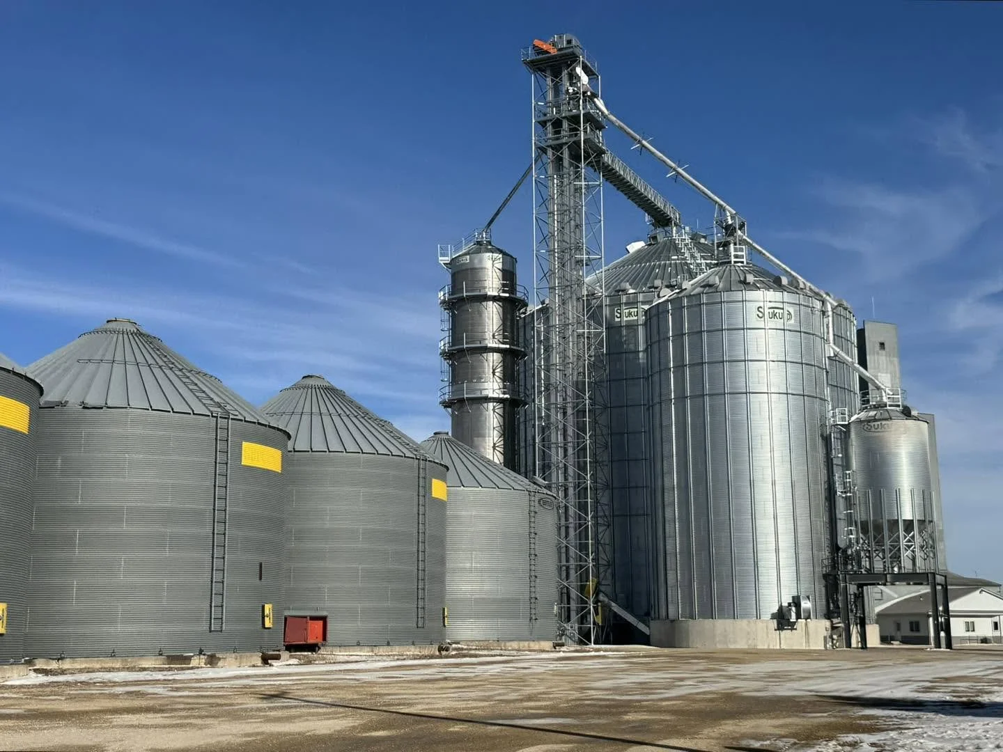 Large industrial grain silos made of metal under a blue sky